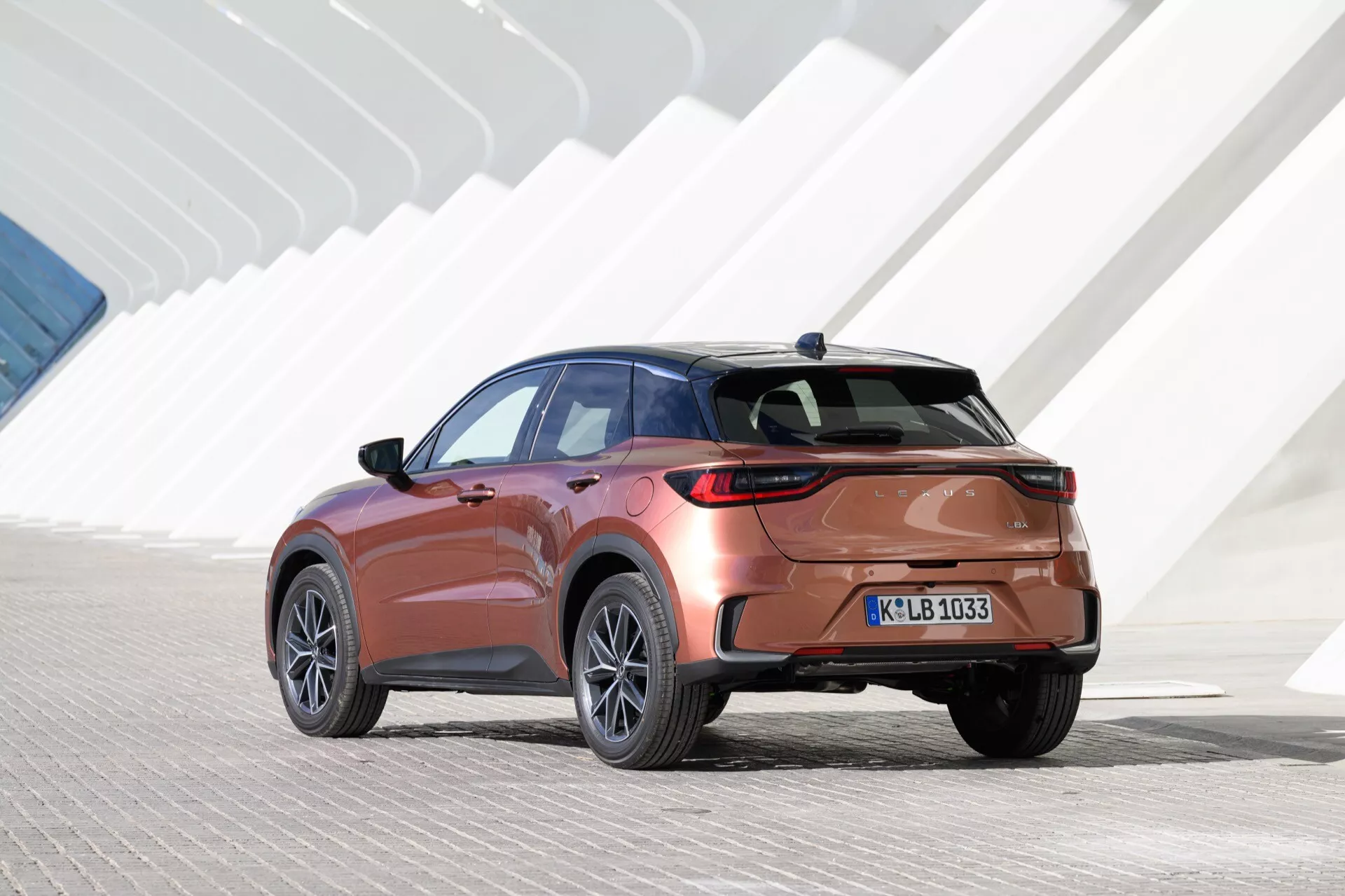 Lexus LBX 2024, 1:a generationen, visar upp sin moderna SUV-design från ett externt bakre tredjedelsperspektiv, framhäver dess aerodynamiska coupé-liknande silhuett, metallisk lack, stora legeringshjul med flerspakdesign, avancerade LED-baklyktor, diskreta märkesbadges, snygga bakre stötfångare och potentiell spoiler eller diffusor, klar bakre vindruta med avfrostare, privat eller tonade sido-fönster, och detaljerad vy av avgas eller underrede betonande prestandaaspekter utan insyn i interiören eller specifika teknikfunktionaliteter