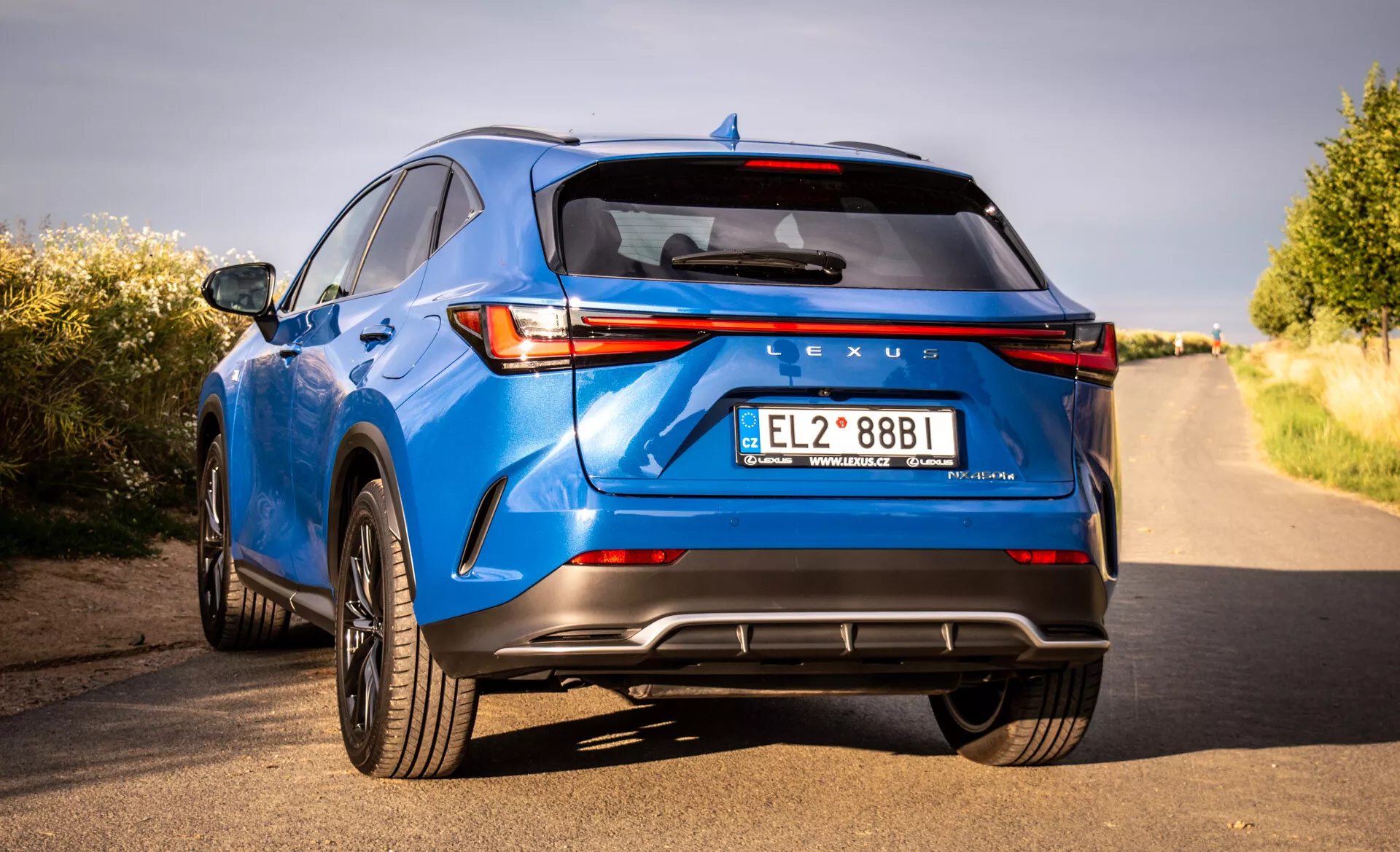Bakifrån vy av en blå 2021 Lexus NX lyxig crossover SUV som visar LED bakljus, Lexus branding, sportig bakre stötfångare med diffusor, dubbla avgasrör och andra tekniska och designfunktioner från ett lågt tre fjärdedels perspektiv