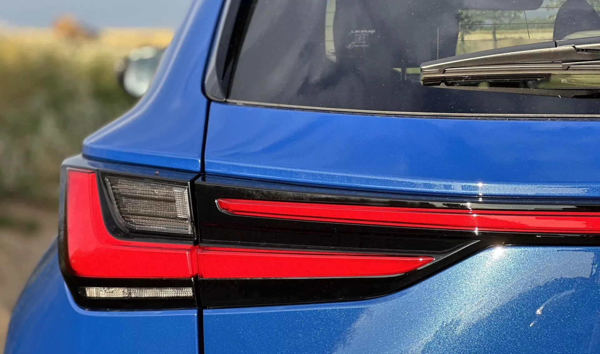 Detaljerad höger baksida av en Lexus NX 2021, som visar den moderna designen på LED-bakljuset, vilket reflekterar dess sofistikerade belysningsteknologi och glansiga blå finish.