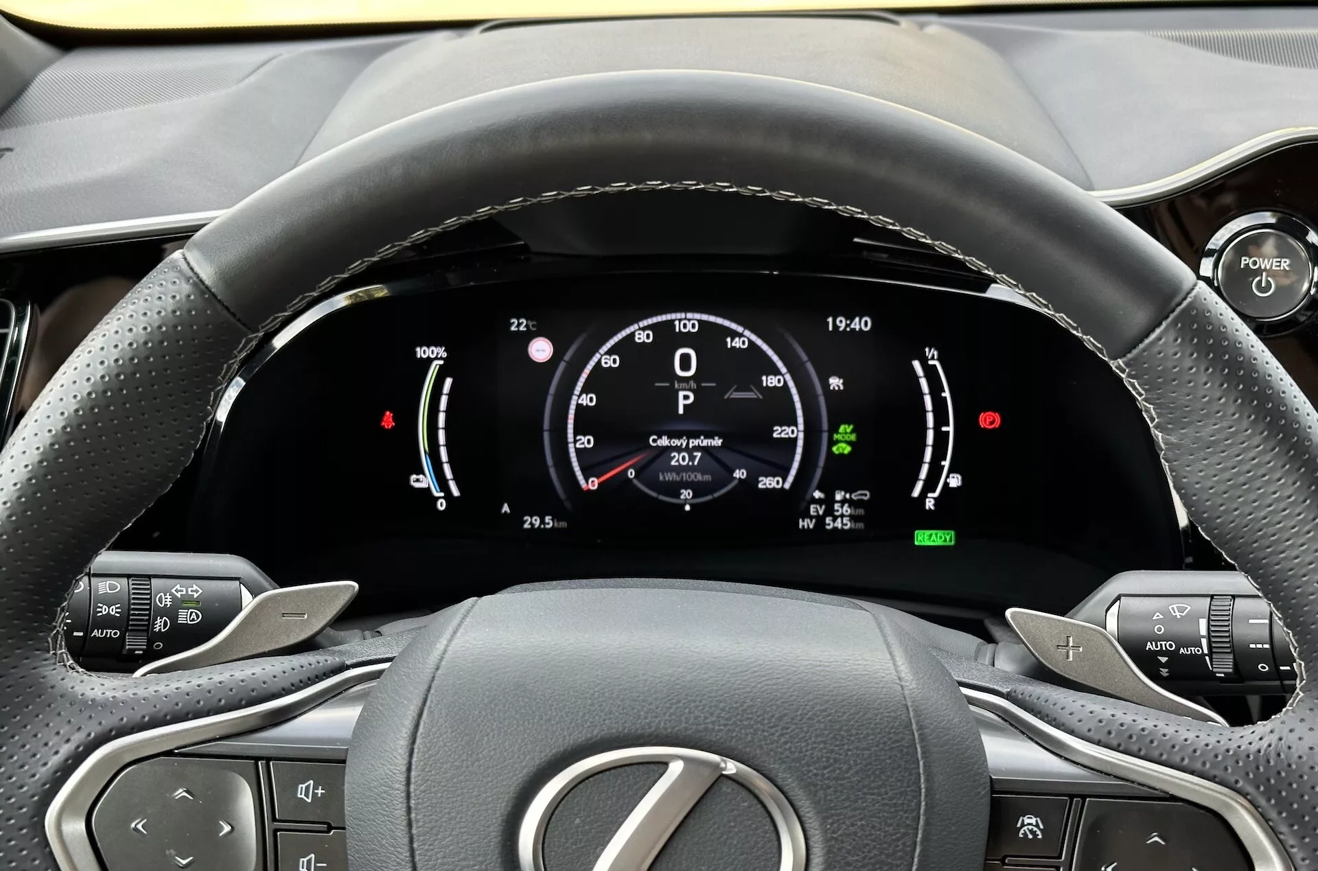 Vy från förarsätet av ratten och den digitala instrumentbrädan på Lexus NX 2021, med fokus på indikatorer för hybridteknik, kontrollknappar för komfort och ergonomisk inredningsdesign