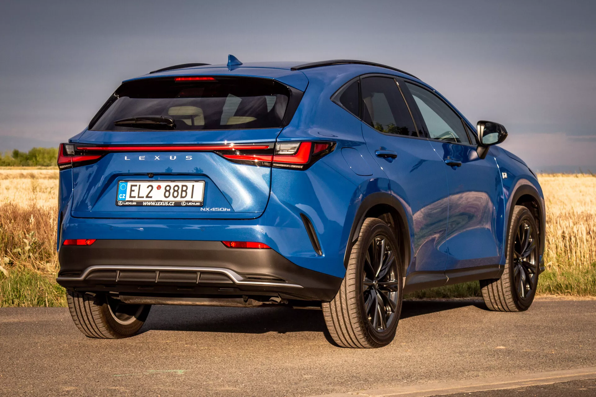 Blå Lexus NX SUV 2021 i tre fjärdedels bakifrån vy som visar designelement och teknikfunktioner på en solig dag med naturlig bakgrund