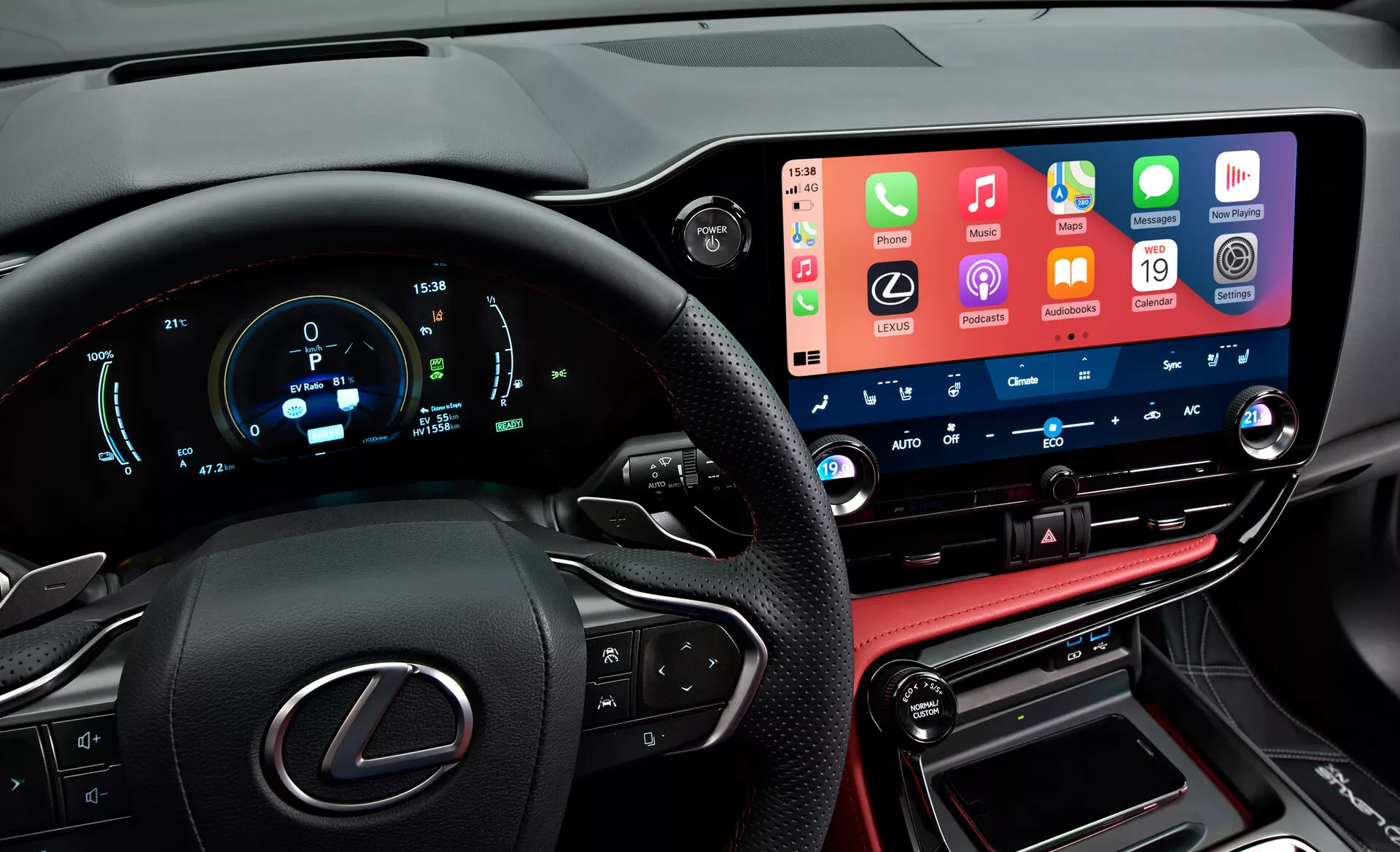Interiörvy av en Lexus NX 2021 som visar en modern, högteknologisk instrumentbräda från förarens perspektiv. Till vänster syns delvis en ratt med Lexus-logotyp och multifunktionella knappar. Den digitala instrumentpanelen visar hastighet, varvtal och andra mätvärden i blått och vitt. Mitt i bilden finns en framträdande bred pekskärms infotainmentsystem som integrerar smartphone-funktioner. Nedanför finns knappar och rattar för klimatkontroll med digitala temperaturdisplayer. Den nedre delen inkluderar en läderstickad konsol med växelspak och anslutningsportar, som återspeglar fordonets lyxiga finish.