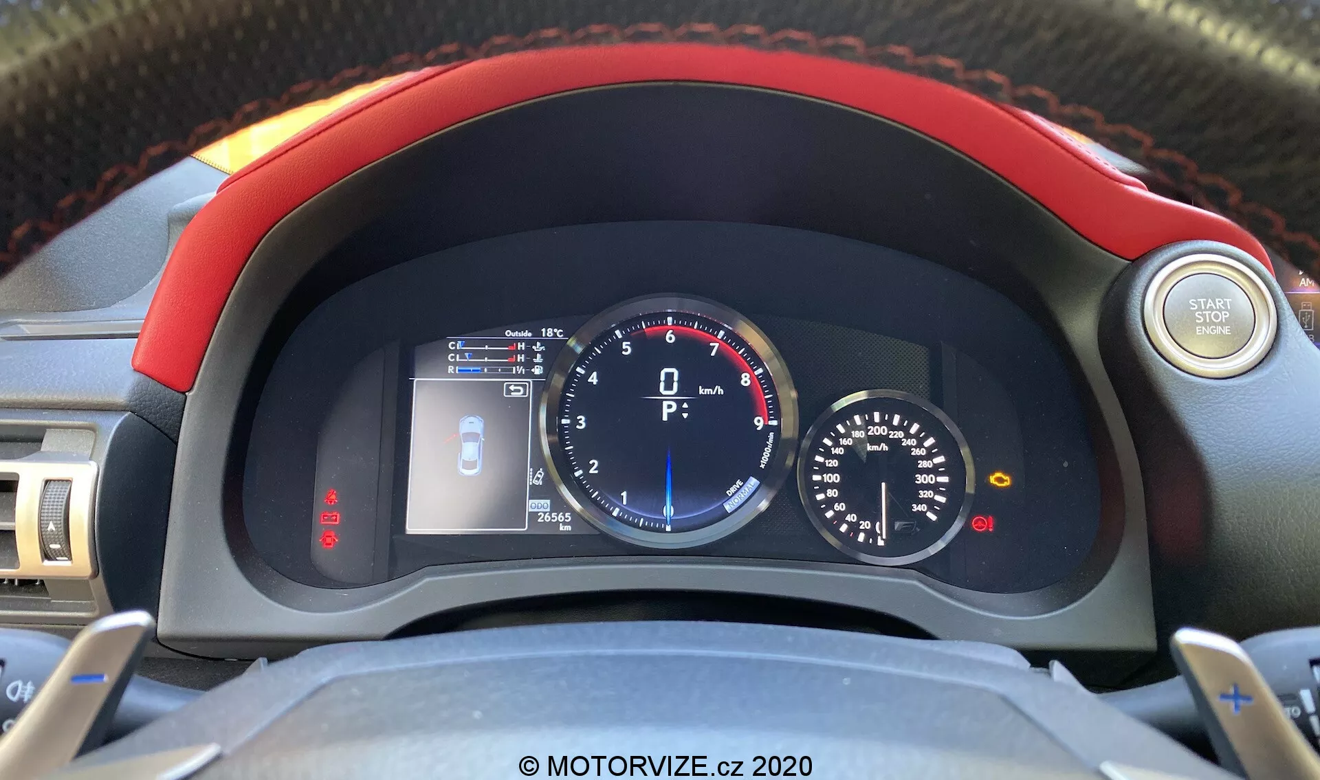Interiörshot av 2016 Lexus RC fokuserat på instrumentbrädan från förarens perspektiv, som visar en ratt med ljud- och farthållarkontroller, en liten LCD-skärm som visar varningsindikator för öppen dörr, motortemperaturmätare, stor analog hastighetsmätare med central digital display, bränslenivåmätare och en mindre varvräknare med nålen i viloläge.