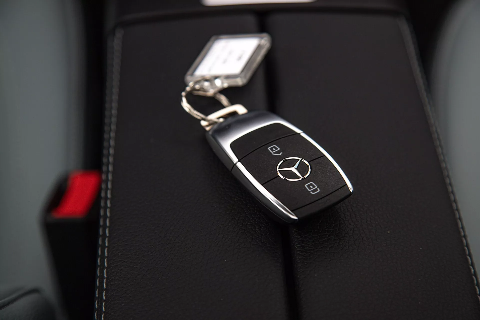Närbild av en Mercedes-Benz A-klass 2022 nyckelfob på lädersäte med logotyp och smarta funktioner