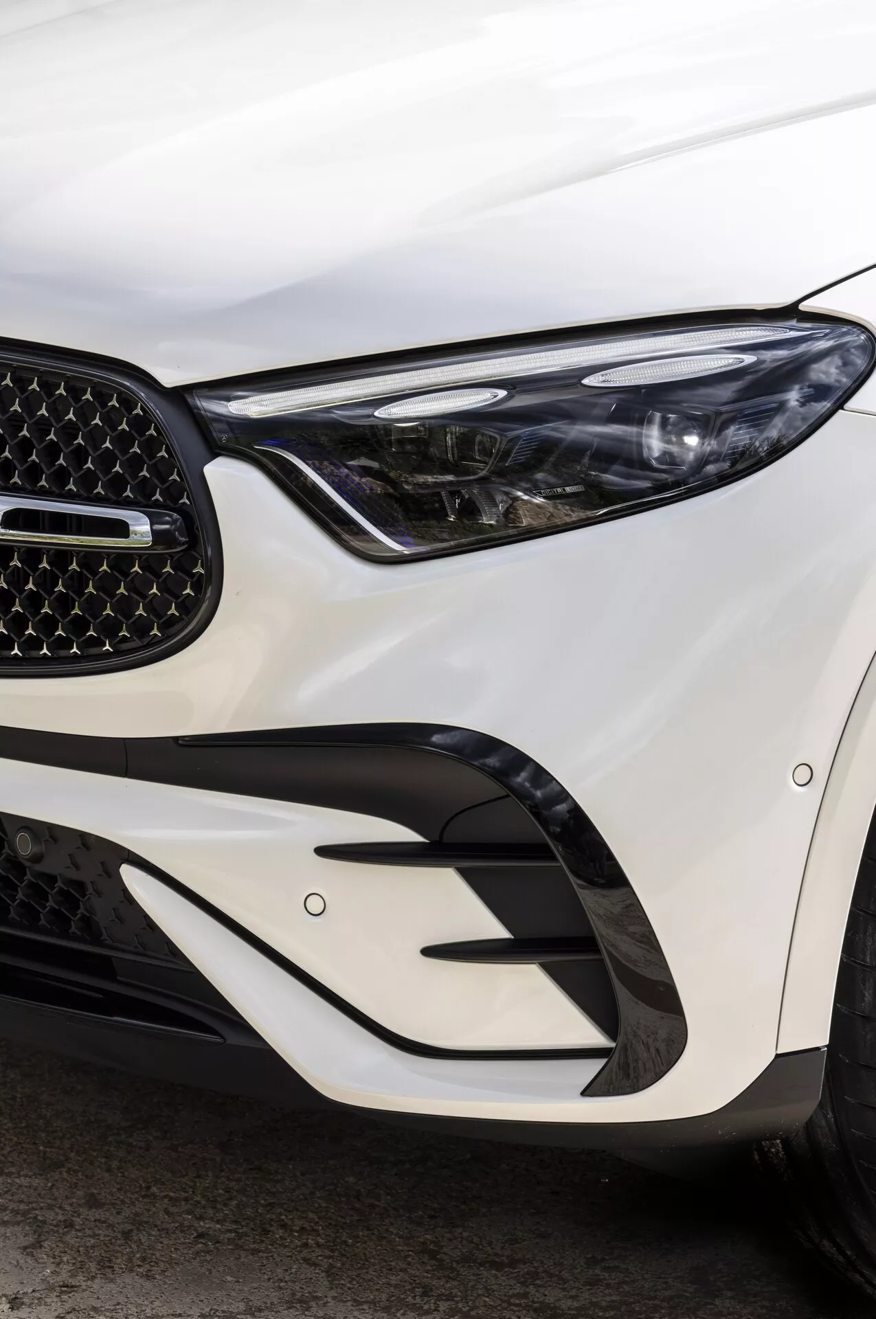 Närbild av framsidan på 2022 Mercedes GLC som visar den eleganta LED-strålkastaren, bikakegrillen och de kantiga stötfångarelementen, fotograferad från en sned vinkel som framhäver avancerad belysning och aerodynamisk design.