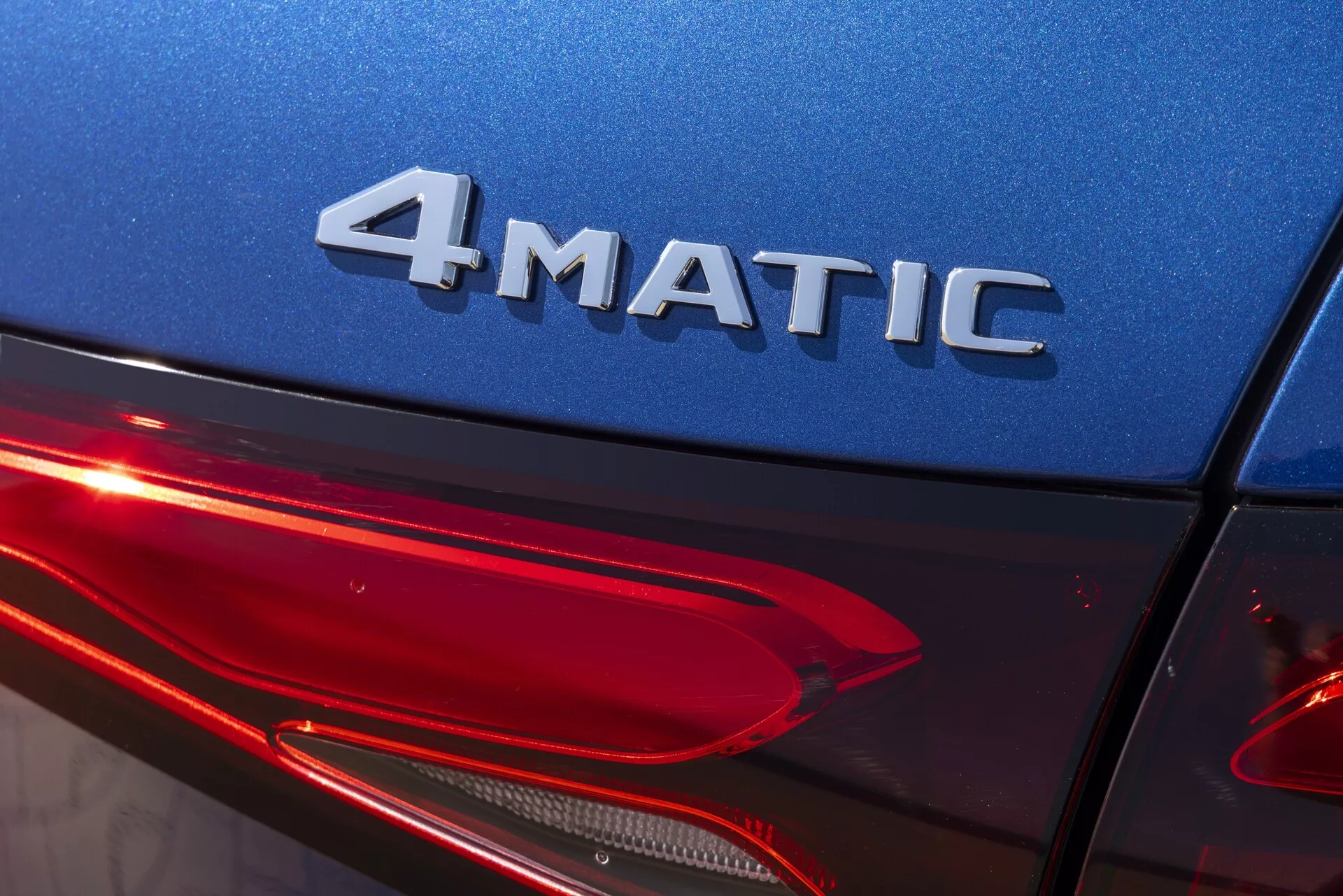 Närbild av bakre delen av en Mercedes GLC 2022 (254) i en lätt uppåtgående vinkel, som visar 4MATIC-märket, en glänsande blå kaross och en modern design av bakljus-LED. Betonar fyrhjulsdriftsteknik, bilbelysning och högkvalitativ yttre finish.