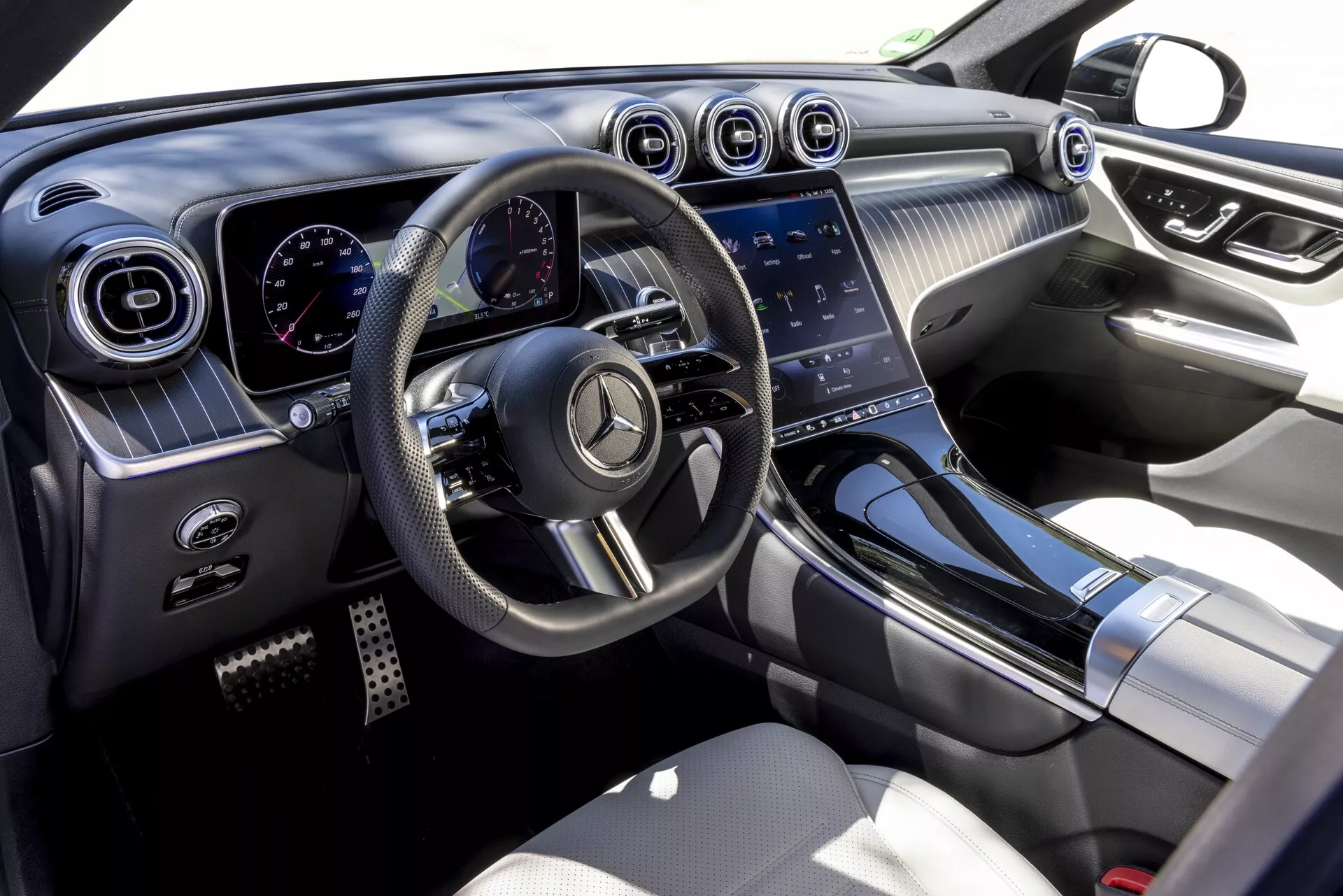 Interiör vy av Mercedes GLC 2022 (254) från passagerarsidan, som visar den moderna och lyxiga designen med multifunktionell planbottnad ratt, digital instrumentpanel, runda luftventiler med kromade accenter, stor pekskärms infotainmentsystem och högkvalitativa material såsom mjuka ytor, metallaccenter och lädersäten.