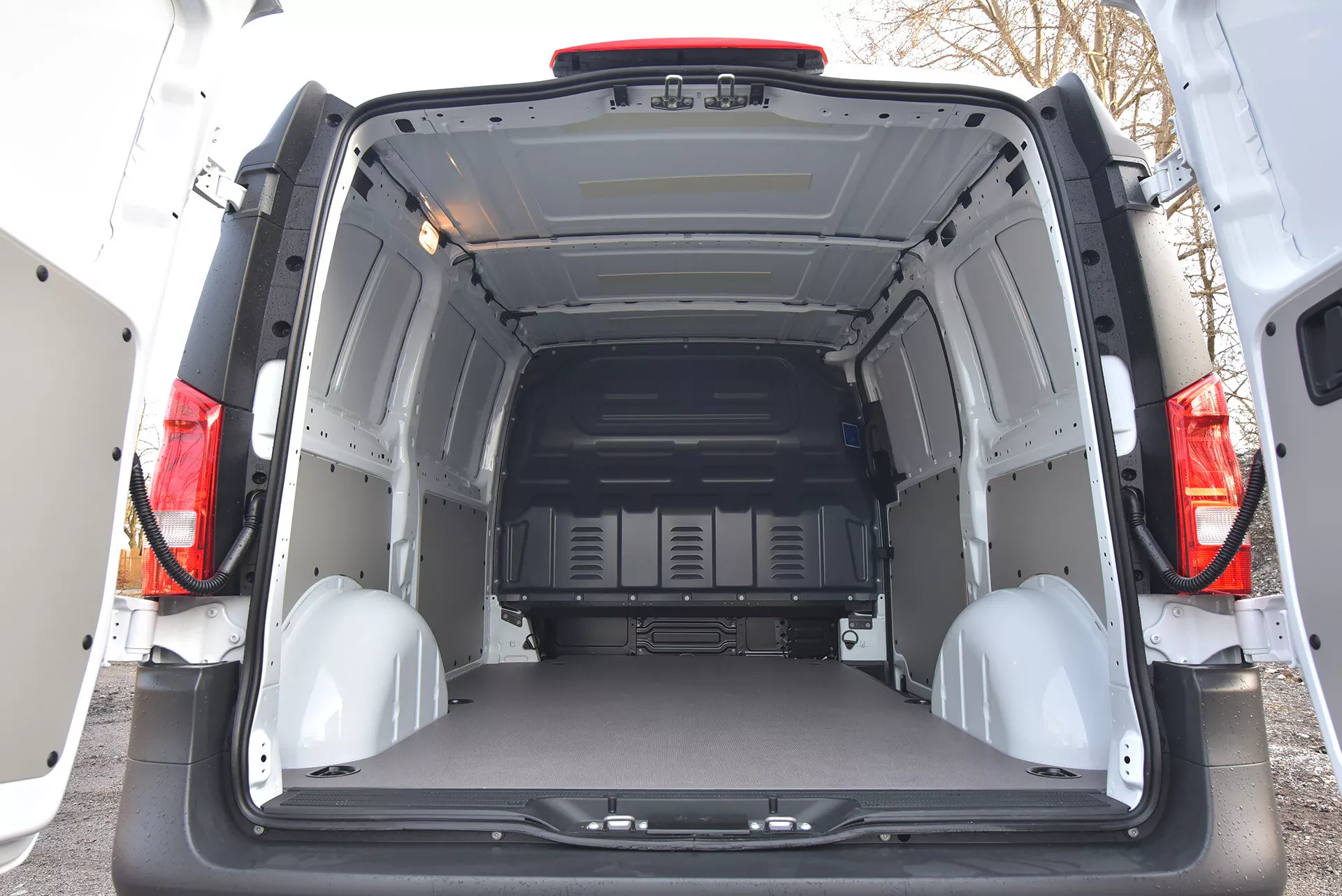Baksida interiörvy av en Mercedes-Benz Vito Tourer 2014 som visar ett rymligt och tomt lastutrymme med öppna dörrar, skyddspaneler och fästpunkter
