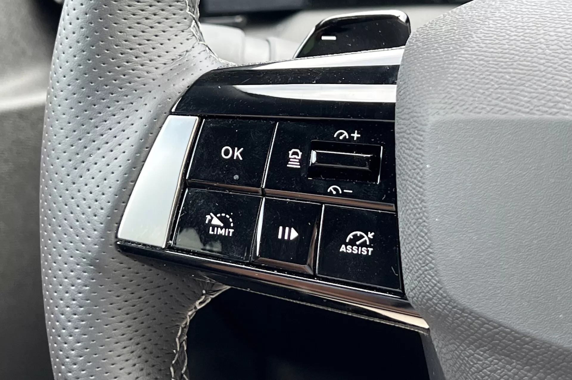 Närbild av knappklustret på ratten i Opel Astra 2022 som framhäver avancerade körfältsassistansfunktioner, inklusive adaptiv farthållare och filhållningsassistans, med fokus på funktionsmärkningar som OK, +, -, LIMIT och ASSIST ur förarens perspektiv