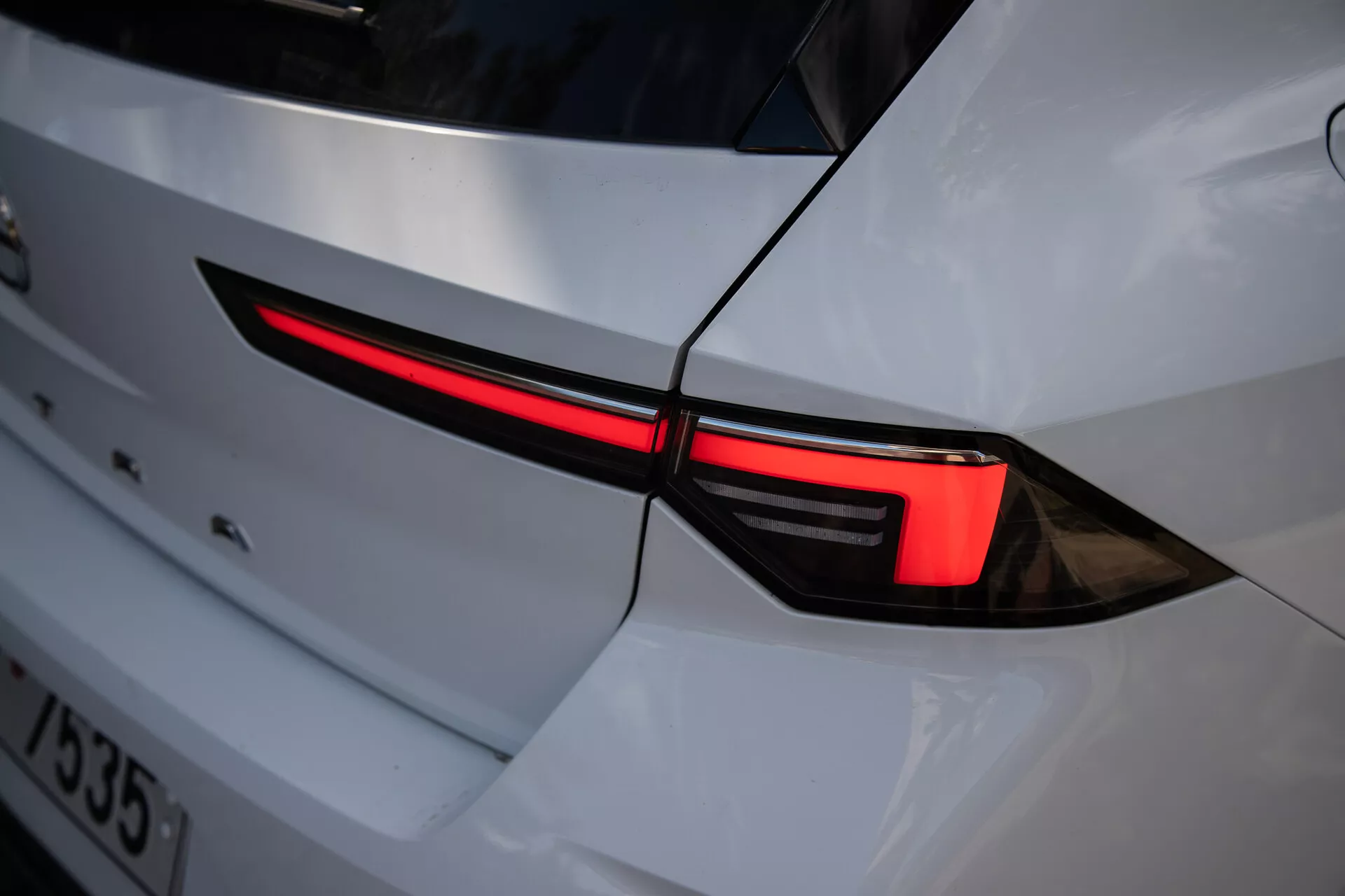 Närbild av 2022 Opel Astras vänstra bakljus, som visar en elegant LED-design och integration i vit kaross med en sportig estetik