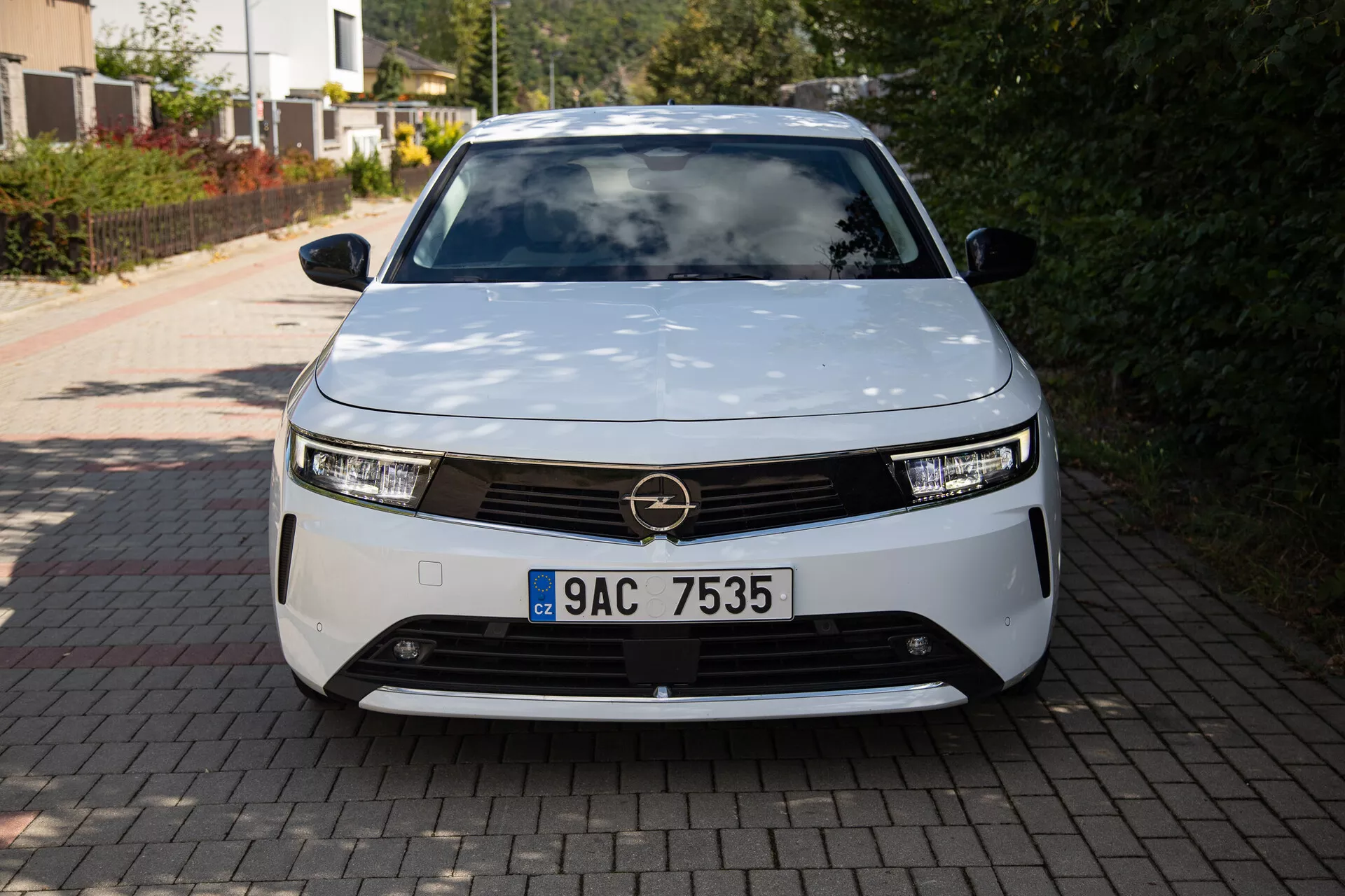 Frontvy av Opel Astra 2022 som visar en modern elbil design med LED-strålkastare, dekorativ grill och aerodynamisk form, parkerad på en bostadsuppfart