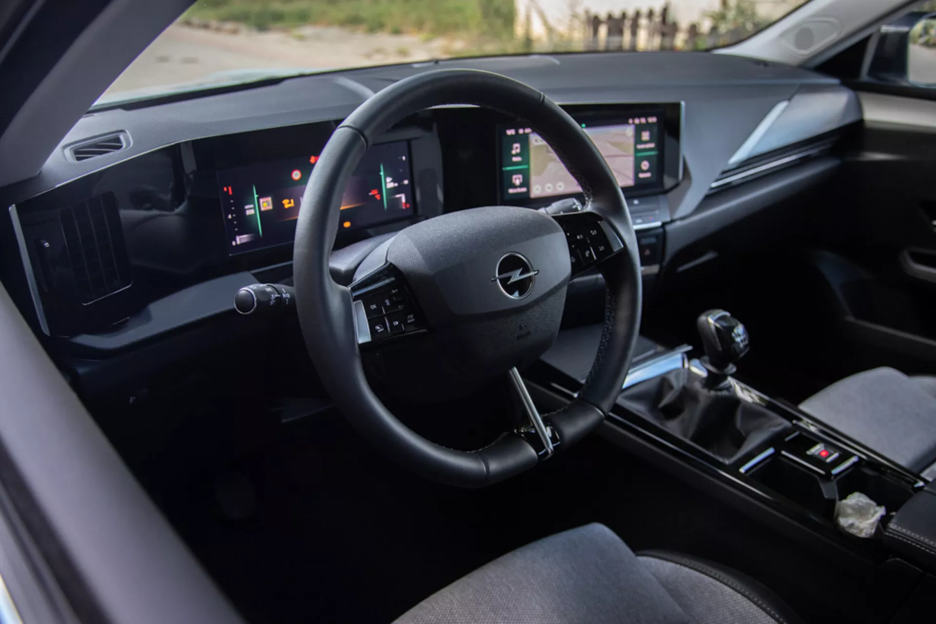 Interiör av Opel Astra 2022 som visar förarsätet, en teknologiskt avancerad instrumentbräda med Opel-logotypen på ratten, digitala mätare och dubbla vertikala pekskärmspaneler