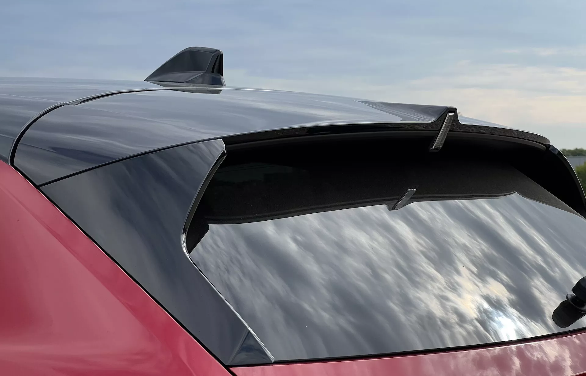 Närbild av en 2022 Opel Astras blankröda bakdel med en snygg spoiler och hajfenantenn, betonar den stora, aerodynamiska bakrutan med potentiellt UV-skyddande toning.