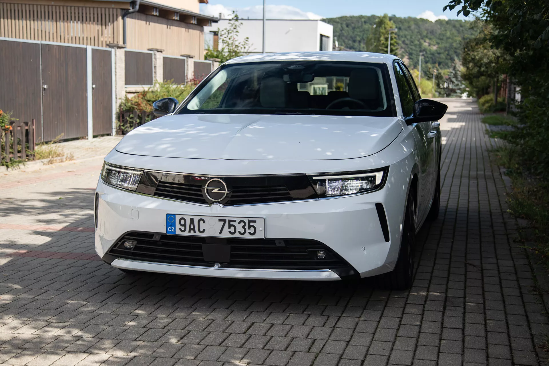 Framifrån och tredjedels sida vy av Opel Astra 2022 som lyfter fram LED-strålkastare, minimalistisk grilldesign, delvis synliga legeringshjul och släta karosspaneler på en europeisk bostadsgata