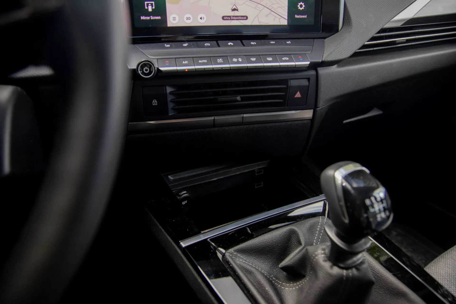 Interiörvy av Opel Astra 2022 med fokus på mittkonsolen och manuell växelspak ur förarens perspektiv, visar ratt, lyxiga designdetaljer och modernt infotainmentsystem.
