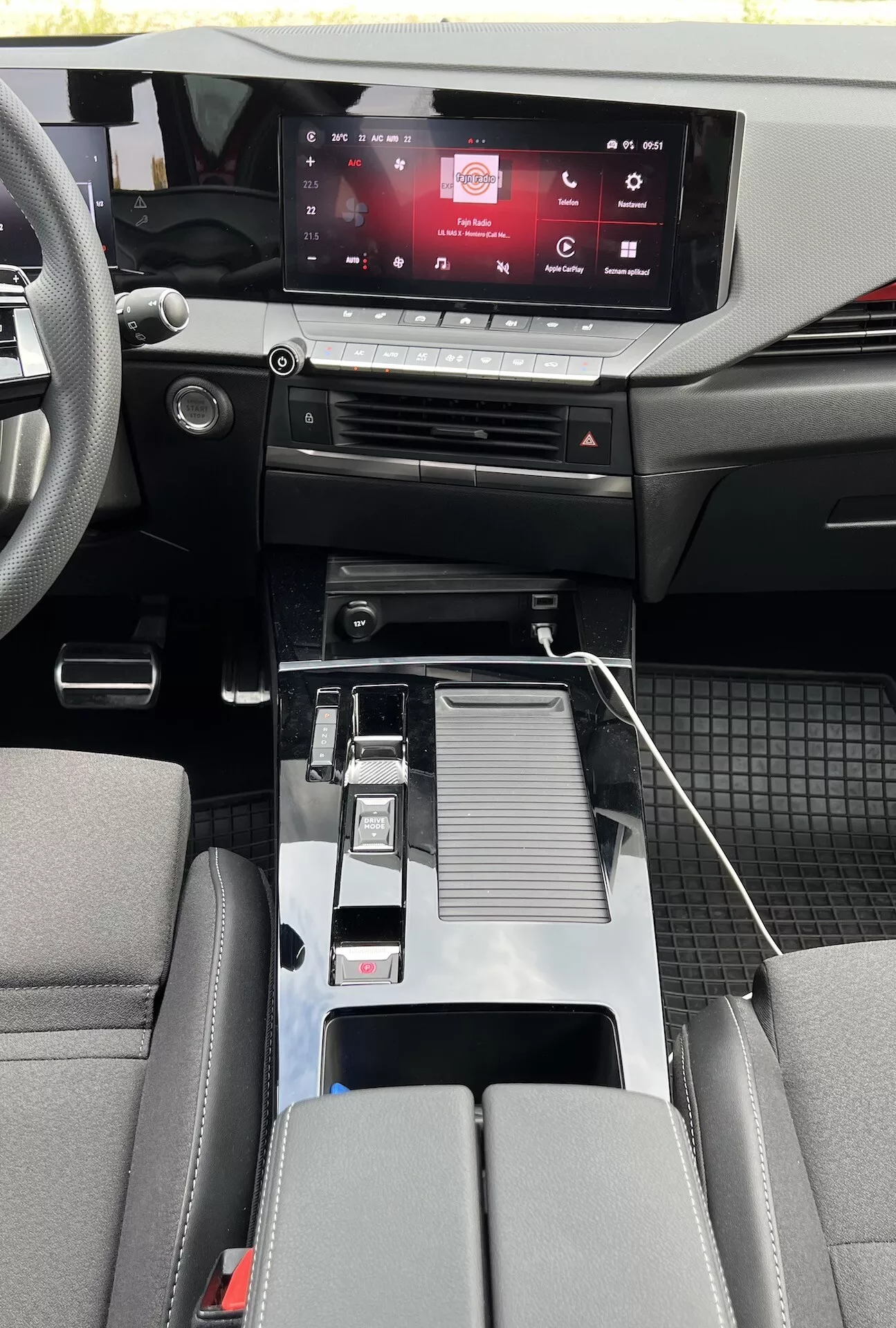 Interiörvy av Opel Astra 2022 som visar modern kabin design med pekskärmsinfotainmentsystem, beröringskänsliga klimatkontroller, metallisk växelspak, USB-anslutning, mugginnehavare, detaljerad mittarmstöd, tvåtonade bilsäten och blandmaterialskabin detaljer med hållbara golvmattor