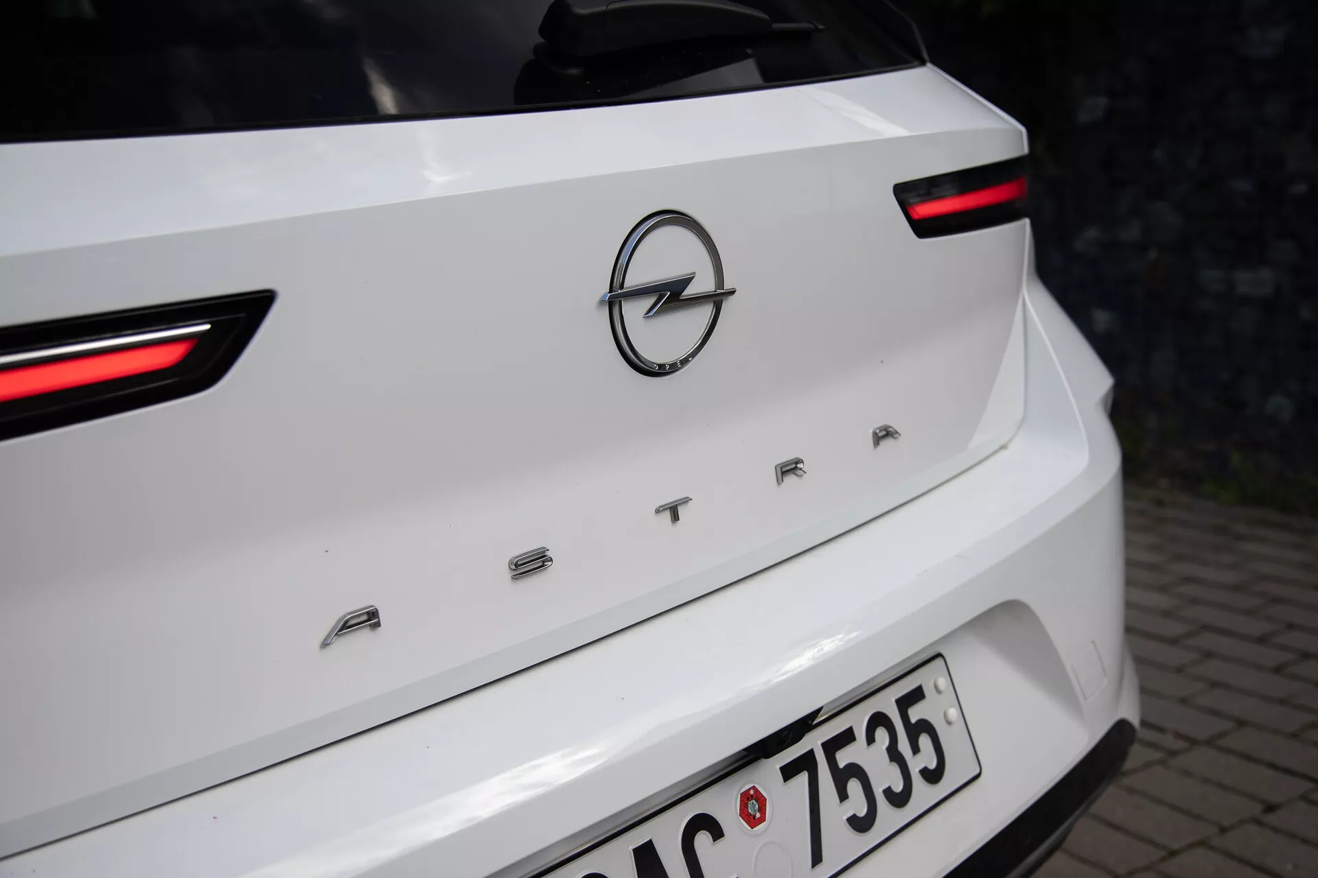 Närbild av baksidan på en vit Opel Astra från 2022, som framhäver LED-bakljusen, Opel-logotypen och modellnamnet 'ASTRA' på bagageluckans lock