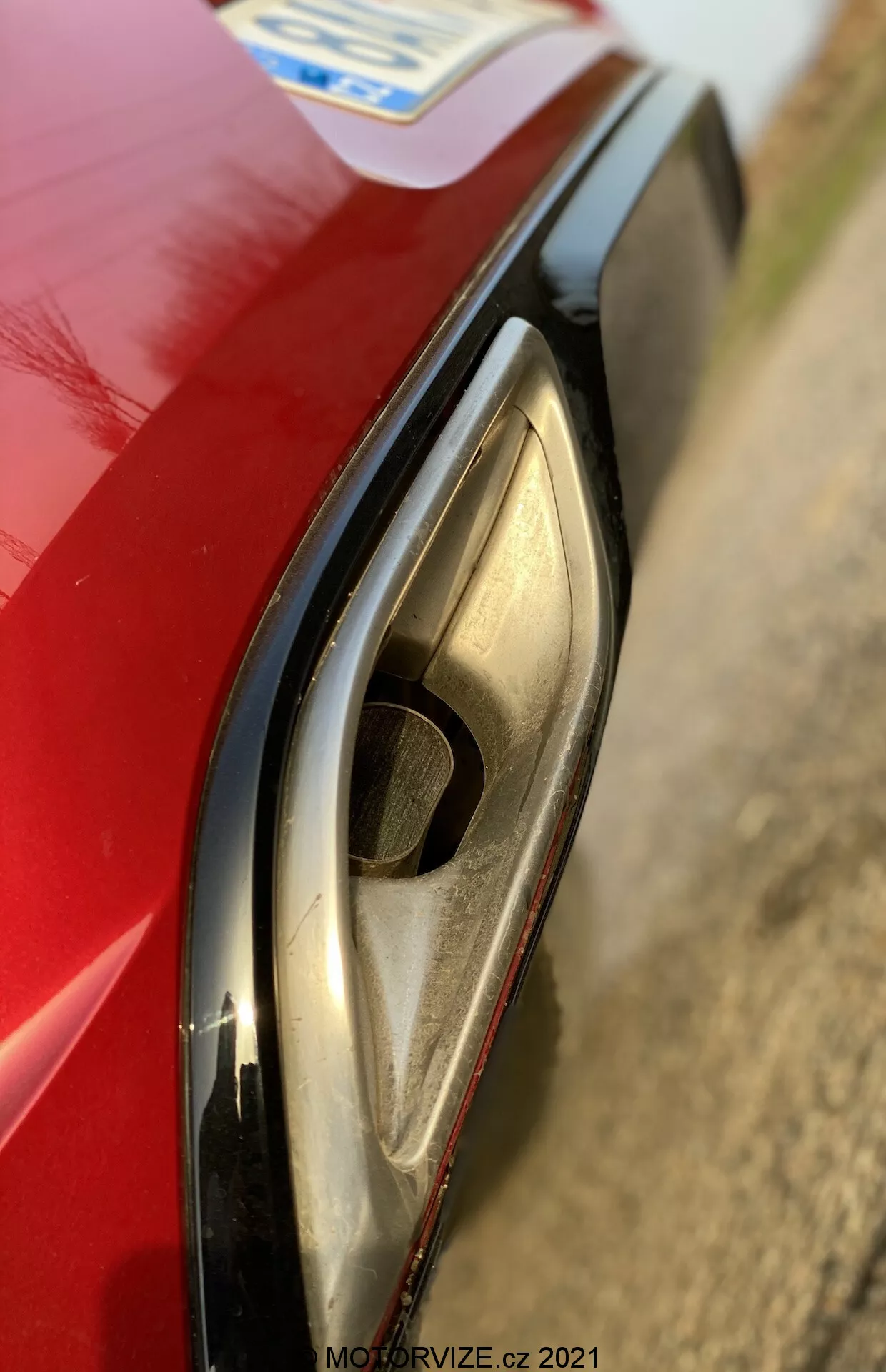 Närbild av Opel Insignia 2020 GSi Grand Sports vänstra framstrålkastare, som visar dess moderna LED- eller HID-teknik. Perspektivet från något ovanför betonar strålkastarens distinkta kurva, det klara höljet, de integrerade blinkljusen eller dagljusen och den röda framskärmen. Det grunda skärpedjupet fokuserar på strålkastaren, med en suddig bakgrund.