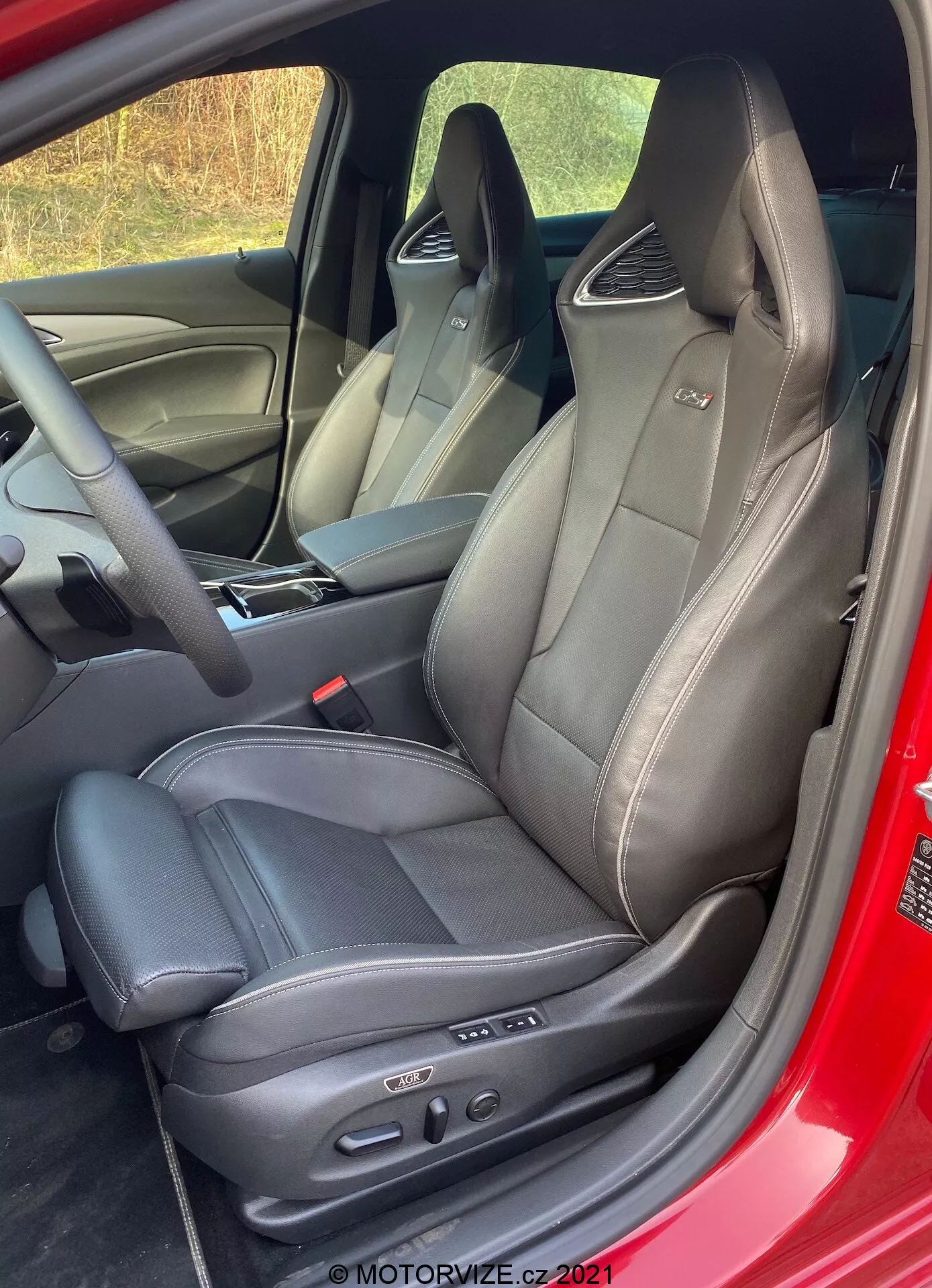 Närbild av interiören i Opel Insignia GSi Grand Sport 2020 som visar svarta lädersäten med framträdande sömmar från en något upphöjd och diagonalt vinkel, med integrerat nackstöd, elektronisk kontrollpanel samt delvis synlig dörrpanel och instrumentbräda.