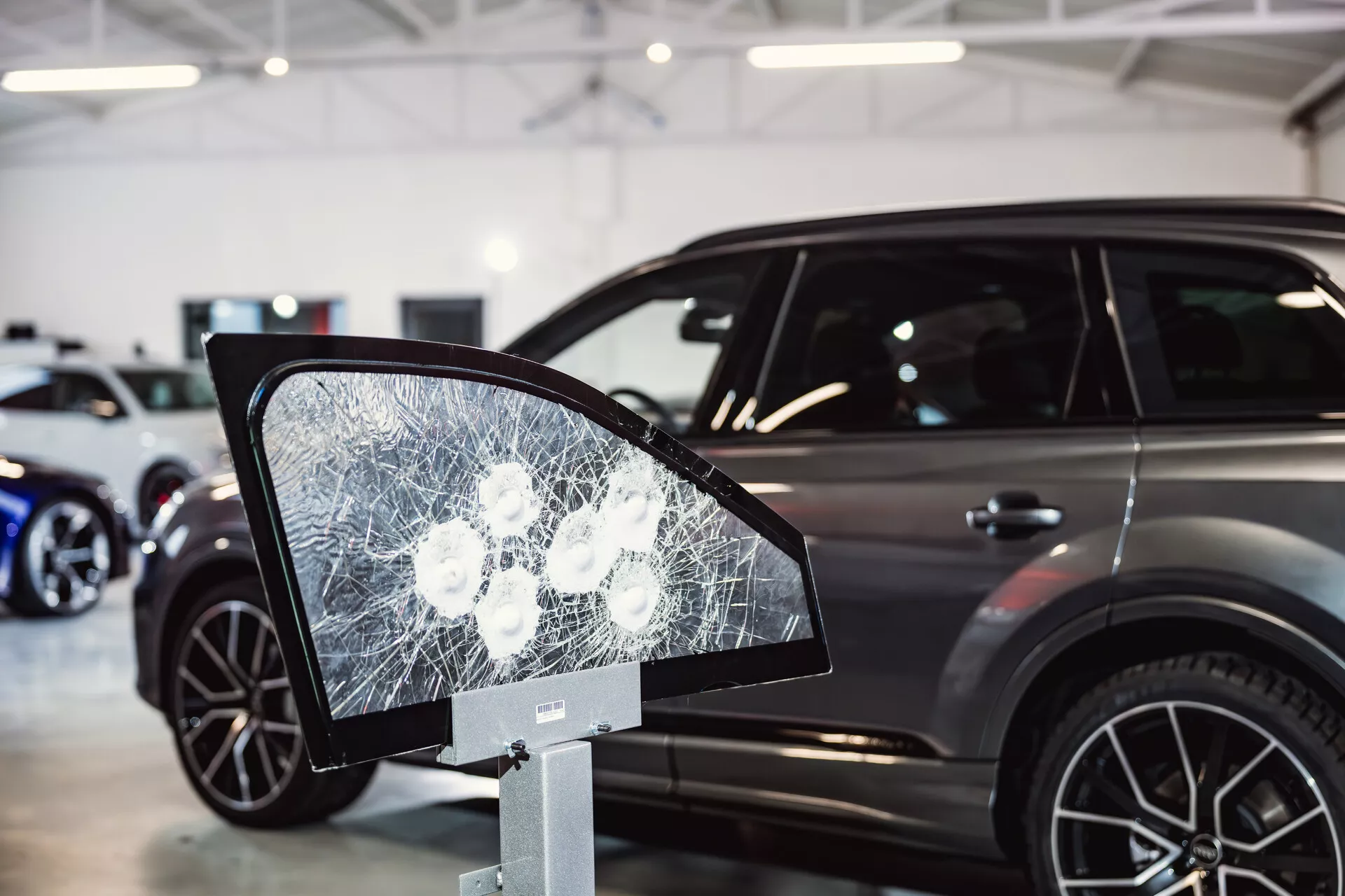 Peugeot 308 2022 modell utställd i showroom med fokus på krossad glasdisplay som liknar en sidospegel i förgrunden, antyder om säkerhetsfunktioner eller hållbarhetstester, och presenterar bilens snygga sidoprofil med moderna SUV-kännetecken i bakgrunden