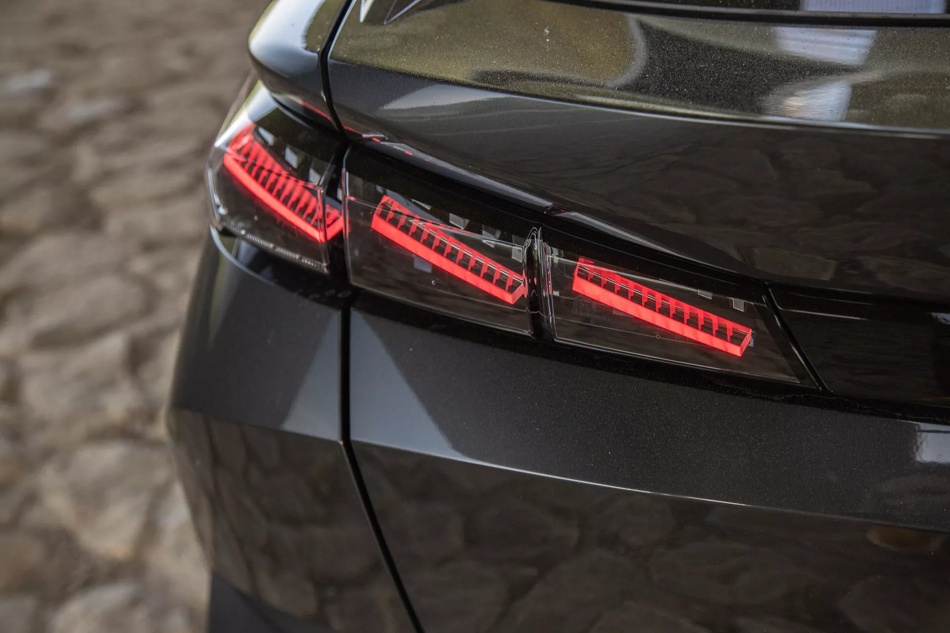 Närbild av de glansiga svarta bakljusen på Peugeot 408 2023 med moderna LED-element och snygga designaccents tagna från en något upphöjd vinkel