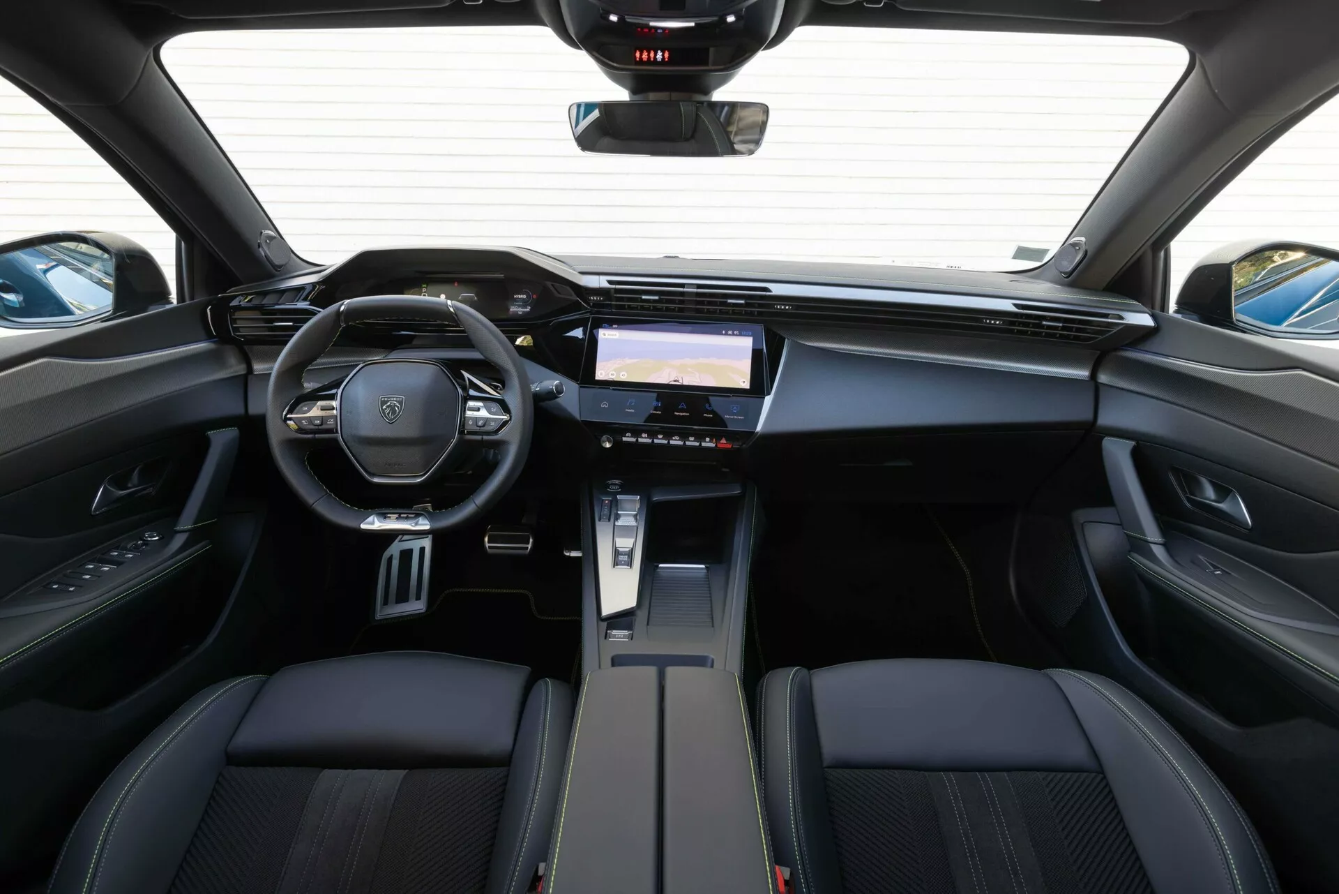 Interiörvy av Peugeot 408 2023 från baksätesområdet som framhäver instrumentbrädan, multifunktionsratten med varumärkesemblem och avancerat infotainmentsystem