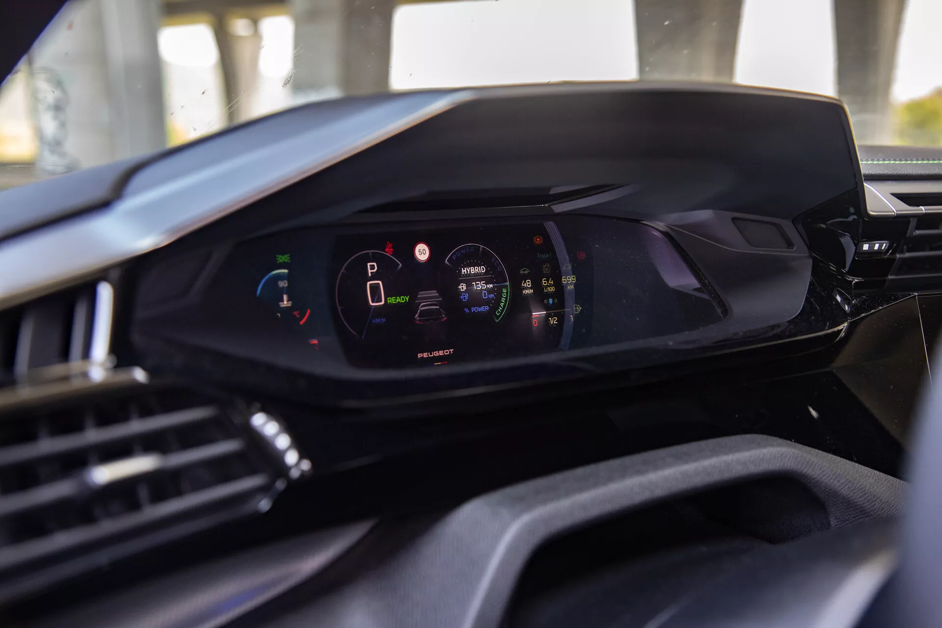 Interiörvy av Peugeot 408 2023 som visar den moderna digitala instrumentbrädan från förarsätets perspektiv, framhävande digitalt instrumentkluster med fordonet i parkeringsläge och hög batteriladdningsnivå