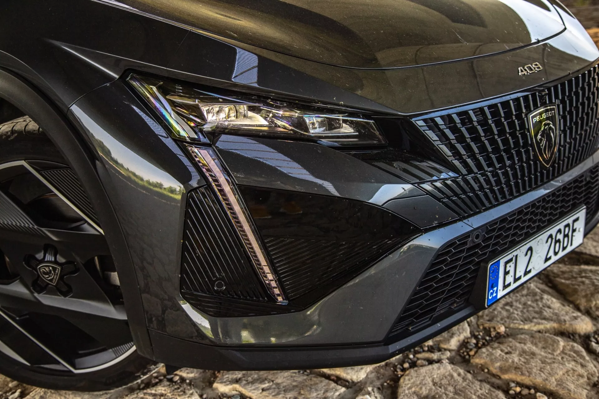 Närbild av främre vänstra hörnet på Peugeot 408 2023 som visar detaljerat strålkastarsamling, grillsektion, motorhuv och hjul med modern LED-teknologi och lyxdesignelement.