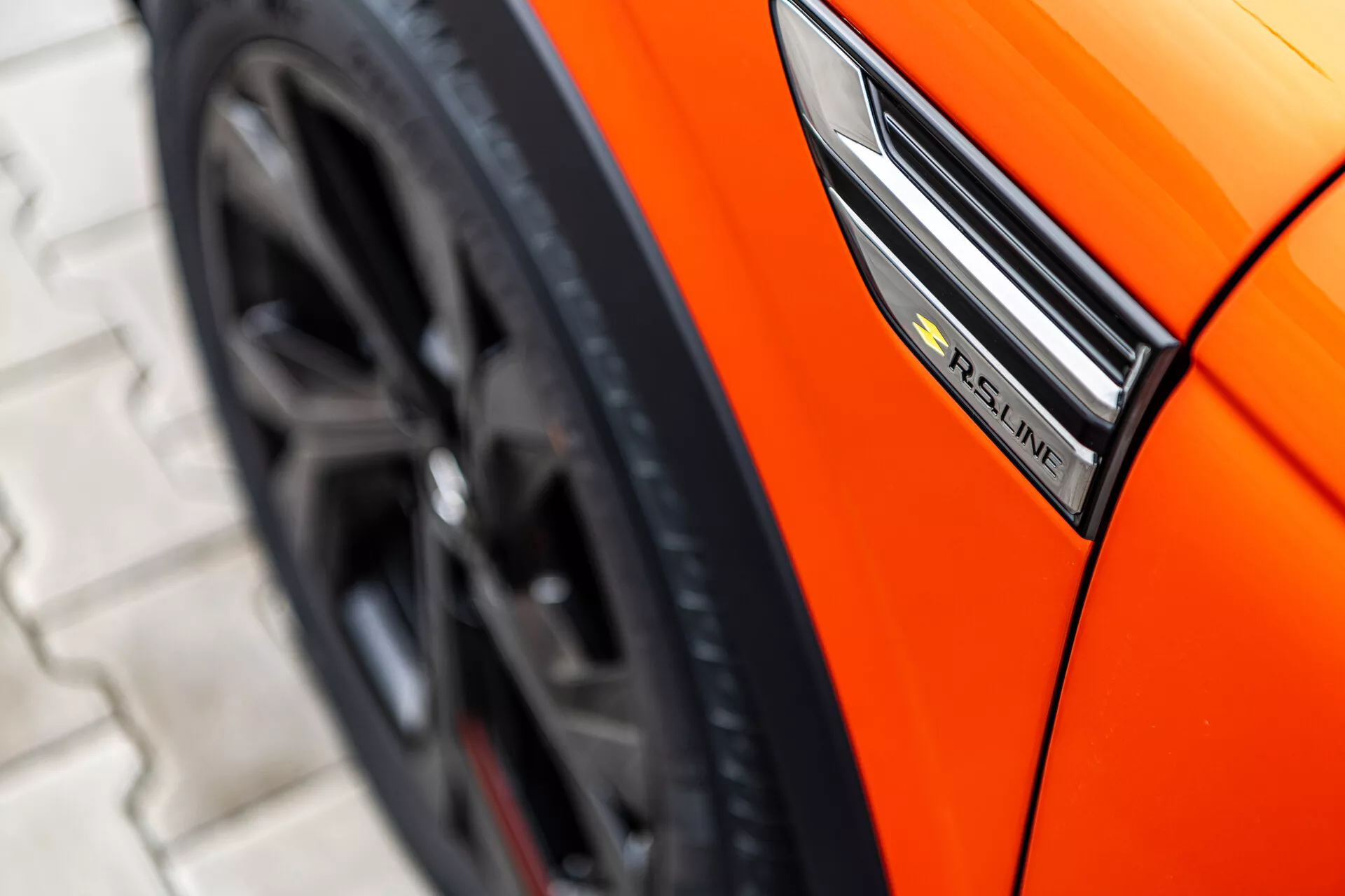 Närbild av en orange Renault Arkana 2021 som visar sidoprofilen med fokus på S-Line-emblemet, skärm och sportig hjuldesign från en låg vinkel