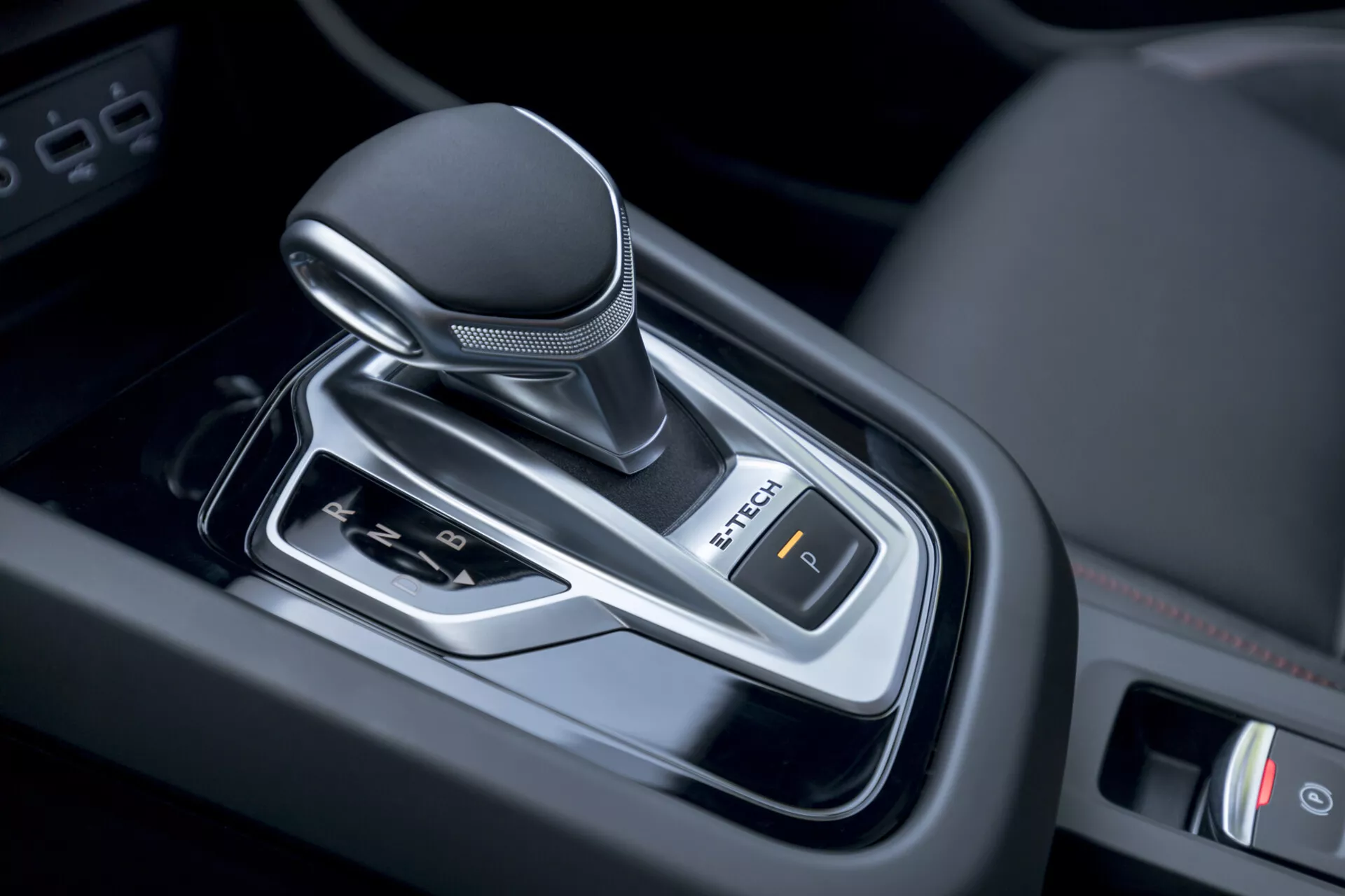 Närbild av en 2021 Renault Arkana automatväxelspak inuti fordonet, som visar modern design med läderinbunden knopp, krom accent och elektronisk parkeringsbromskontroll.
