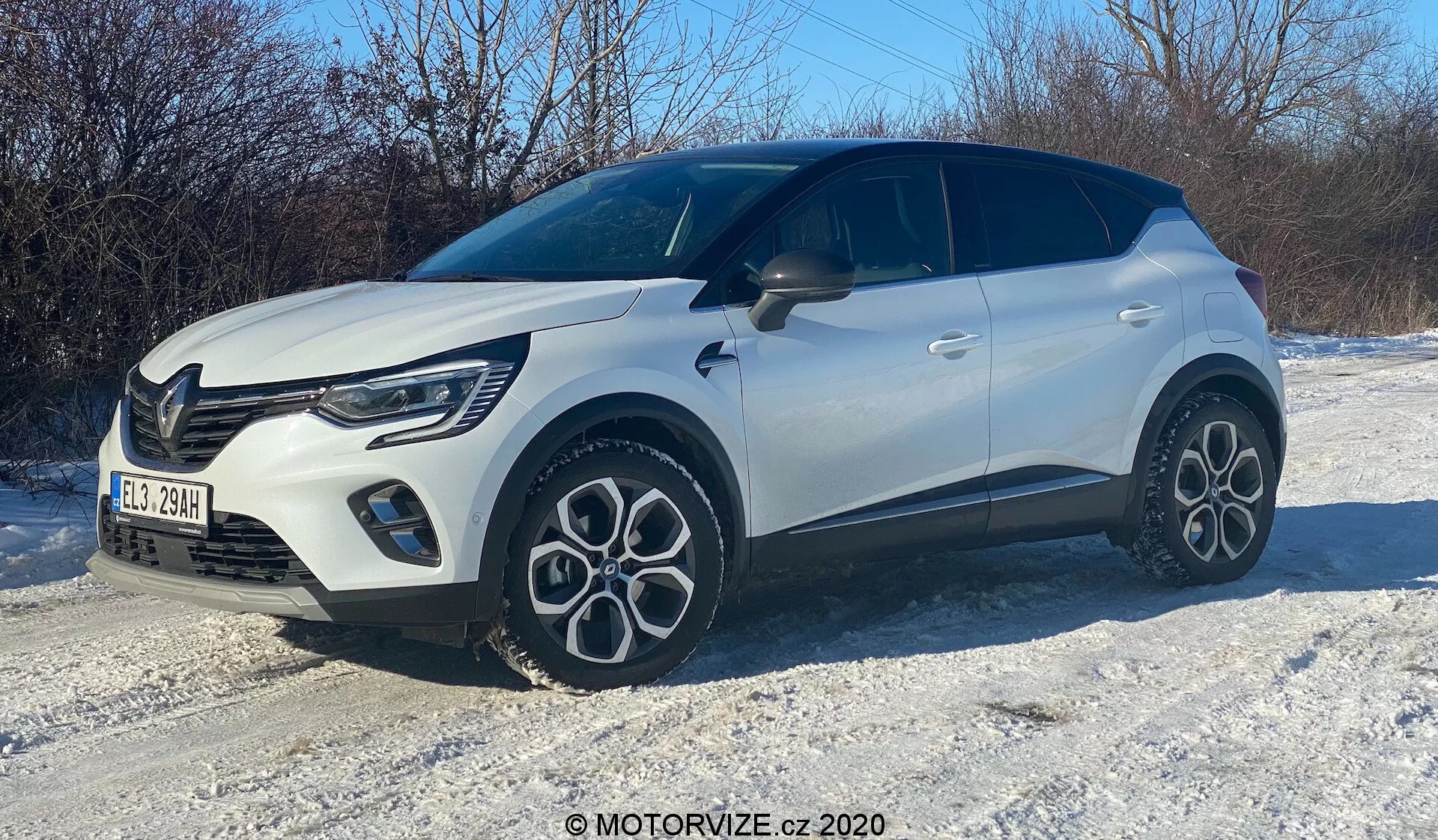Bild av en vit kompakt SUV på snötäckt terräng, fotograferad från en trekvarts framvinkel. Höger sida, motorhuv, grill, eleganta LED-strålkastare, framhjul och skärm, passagerardörr och en del av bakre delen är synliga. Fordonet har en modern design med djärva linjer, distinkta multiekersfälgar, tvåtonskaross med svart tak och ett distinkt grillmönster med synliga dagsljuslampor.