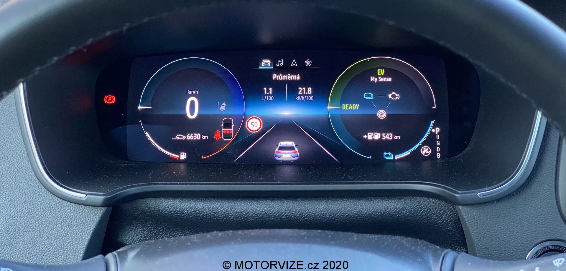 Närbild av Renault Megane 2022 (Megane E-Tech) digitala instrumentpanel tagen från förarens ögonhöjdsperspektiv, som visar en livfull, högupplöst skärm. Skärmen visar en hastighetsmätare med '0 km/h,' adaptiv farthållargrafik, filhållningsassistans, bränslemätare, vägmätare, 'READY'-indikator, varvräknare/effektmätare, batterinivåindikator, körläge ('Normal'), körsträcka, utetemperatur ('11') och strålkastarikon.