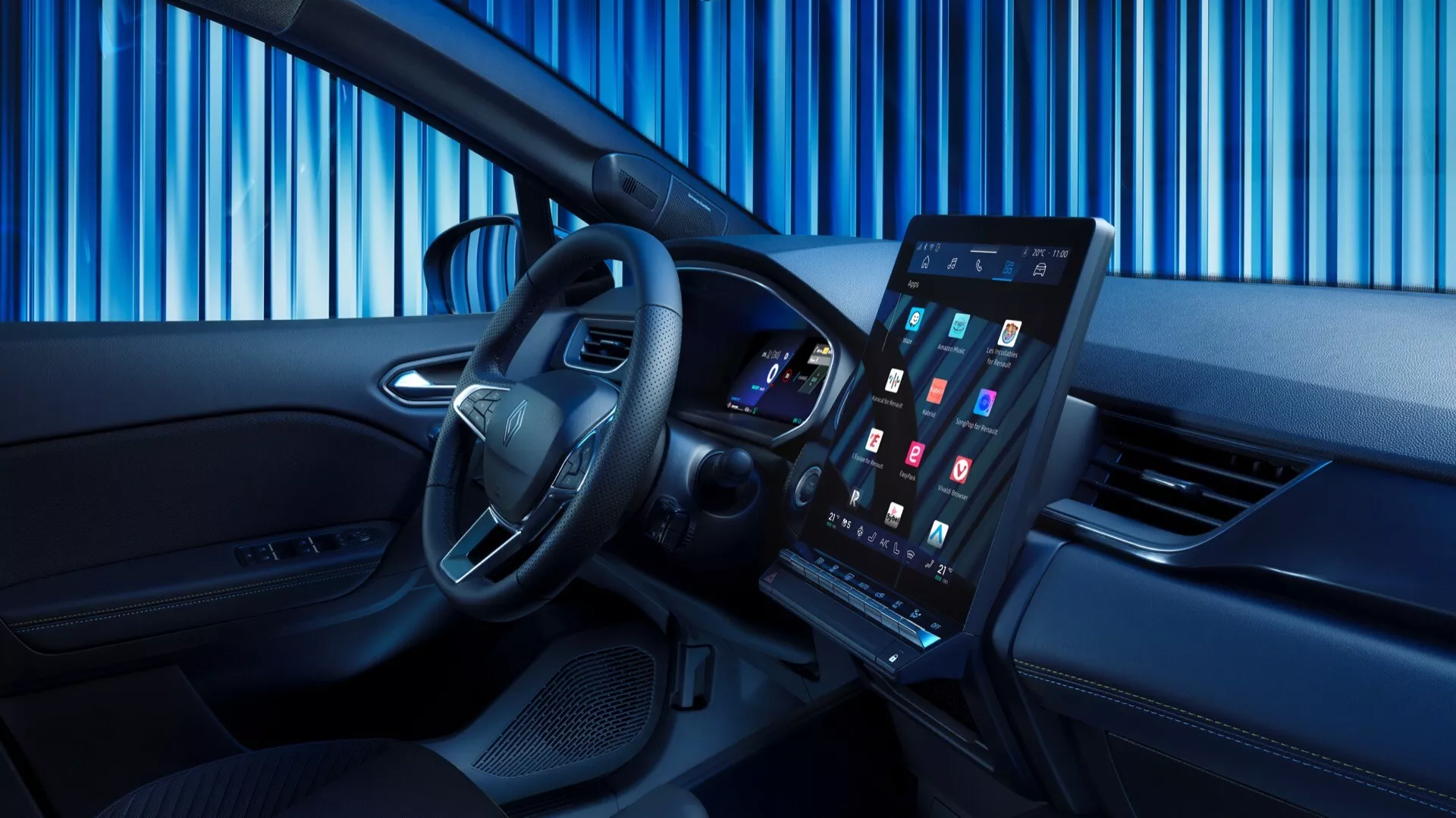 Bilden visar interiören i Renault Symbioz 2024 (1:a generationen) med en modern och sofistikerad design. Bilden är tagen från en något avvikande vinkel mot den främre passagerarsidan, vilket ger en tydlig vy över förarområdet. Ratten, med silverdetaljer och monterade kontrollknappar, är framträdande i förgrunden. Bakom ratten syns en digital instrumentpanel med en färgglad display. Den centrala delen av instrumentpanelen rymmer ett stort, vertikalt orienterat pekskärmsbaserat infotainmentsystem. Inredningen har en tvåfärgad design med högkvalitativa material, en tunn ventilationsöppning under skärmen och kontrollpaneler på förardörren.