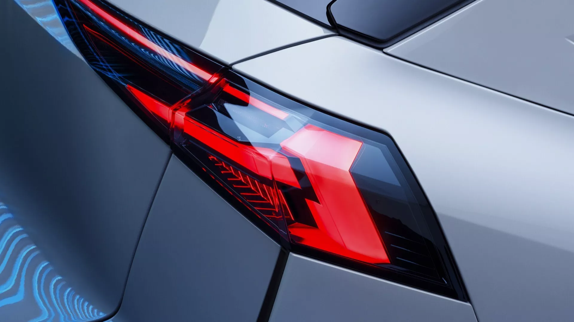 Närbild av Renault Symbioz 2024 generationens bakljusenhet som visar upp intrikat design och avancerad LED-belysningsteknik. Det diagonala, bakre kvartsperspektivet fokuserar på vänster baklykta från en något förhöjd vinkel, vilket framhäver geometriska former, skarpa ljusmönster och särskilda sektioner för broms- och backljus. Baklyktans hölje med kantiga kanter passar tätt in i bilens karosseri med en blank metalliclackering, vilket reflekterar den moderna bilens designegenskaper och tekniska funktioner.