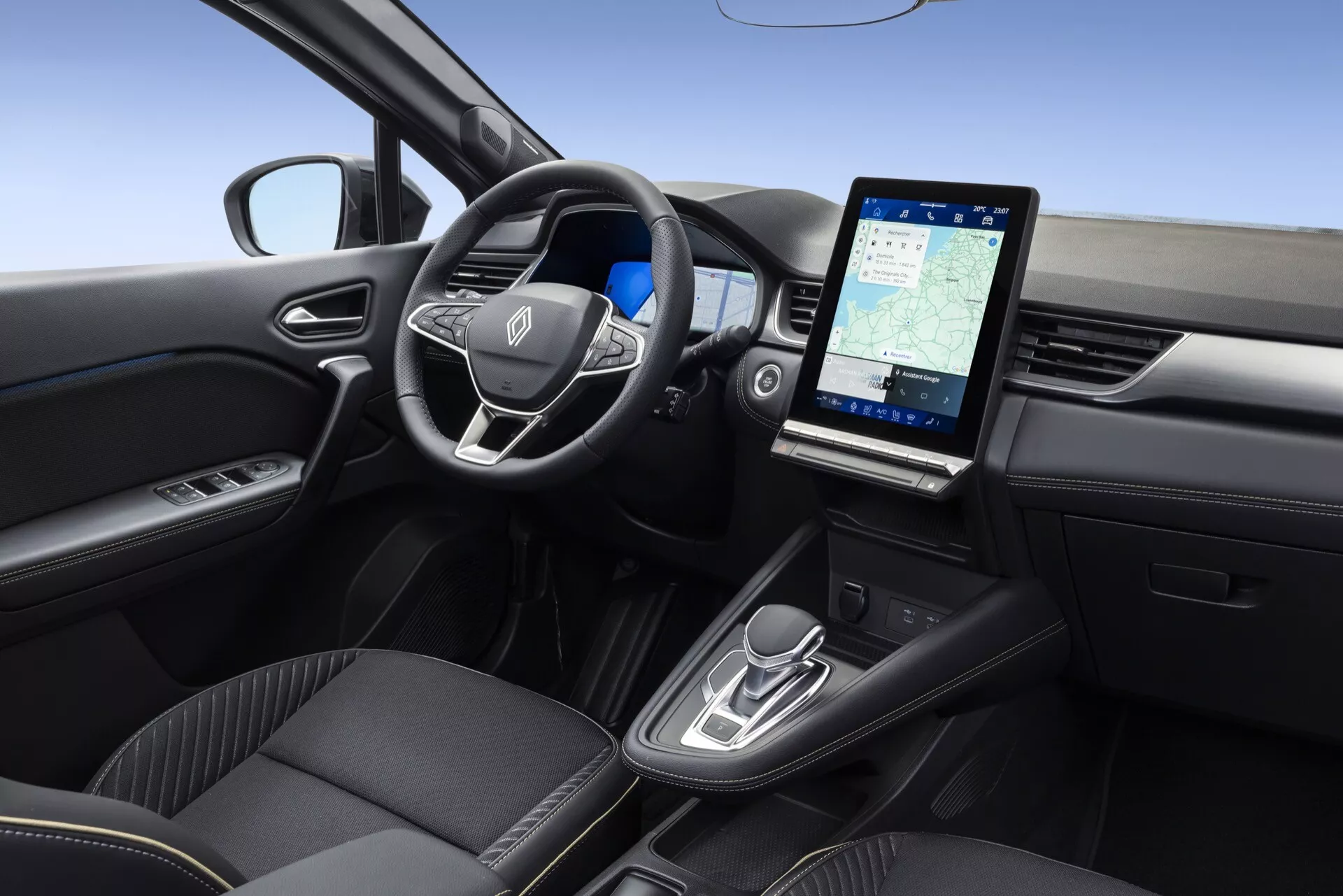 Interiören i Renault Symbioz 2024, visad från en upphöjd, något högervinklad vinkel. Innehåller en multifunktionell ratt med tillverkarens emblem, en minimalistisk instrumentbräda som antyder en digital eller head-up display, ett stort, vertikalt pekskärmsinfotainmentsystem som visar navigering, moderna kontroller för automatisk växellåda, högkvalitativa svarta säten med premiumklädsel och förardörr med elhisskontroller.