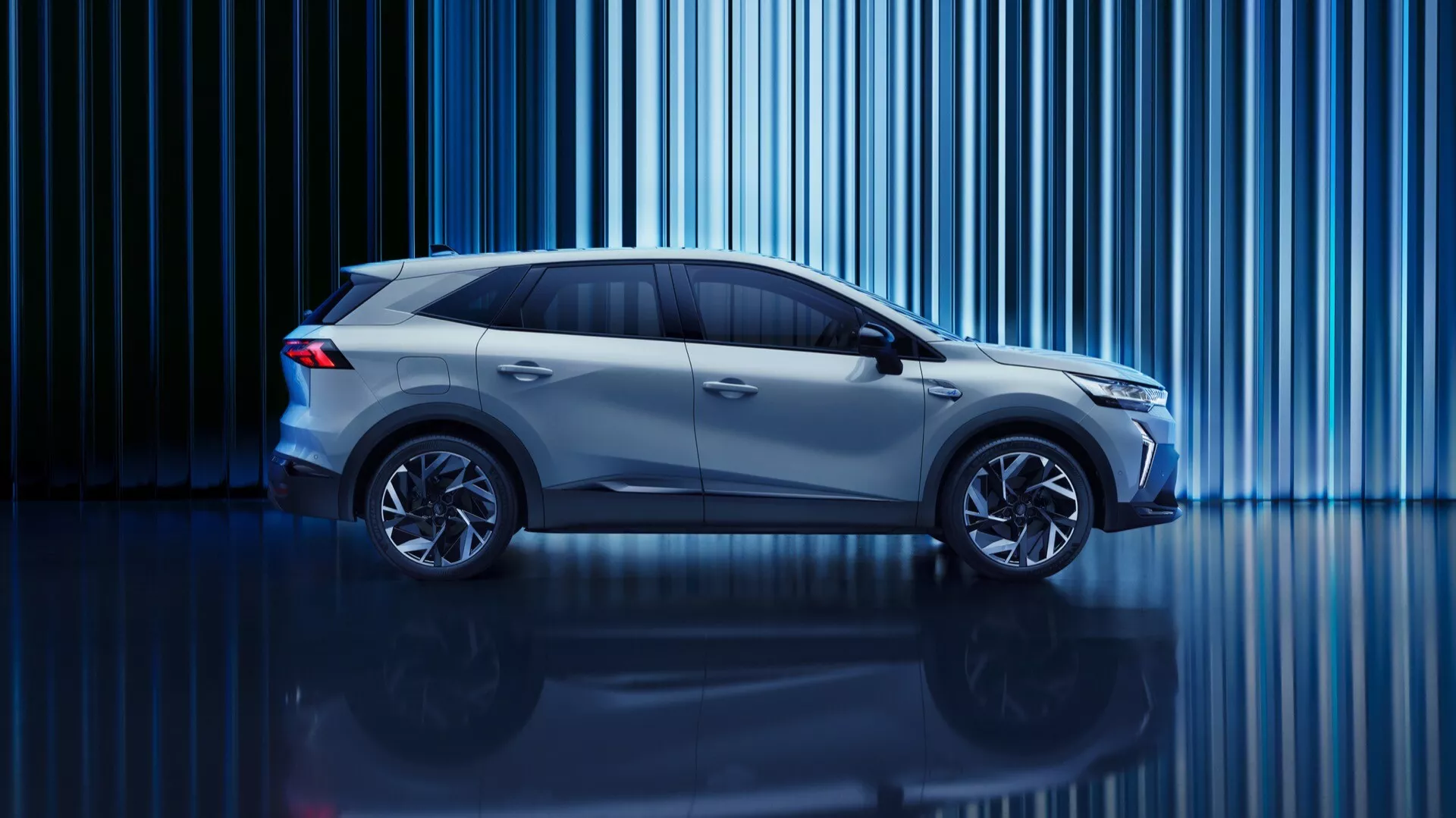 Studiobild av Renault Symbioz 2024 (1:a generation) från en sidoprofilvinkel. Bilen, en kompakt SUV eller crossover med ökad markfrigång, är upplyst av en kreativ belysning med blå ton. Vertikala ljusstreck i bakgrunden och en blank golvyta bidrar till en högteknologisk atmosfär. Modern design som aerodynamiska linjer, stora hjulnav och eleganta sidospeglar är synliga. Tonade sidorutor skvallrar om avancerad interiörteknologi, och designen antyder energibesparande ingenjörskonst, möjligen elektrisk eller hybrid.