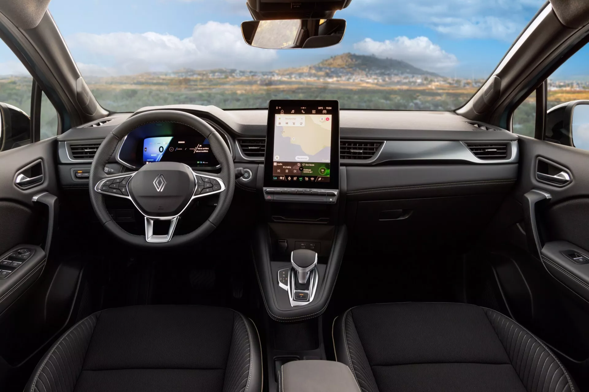 Interiör av Renault Symbioz 2024 första generationen från baksätets perspektiv, som visar instrumentpanelen och främre sittområdet. Innehåller ett centralt placerat platt botten-ratt med multifunktionskontroller, digitalt instrumentkluster, stor pekskärmsinfotainmentsystem, minimalistiska klimatkontroller, modern växelväljare och konturerade säten i läderliknande material, vilket framhäver modern design och avancerad teknik.