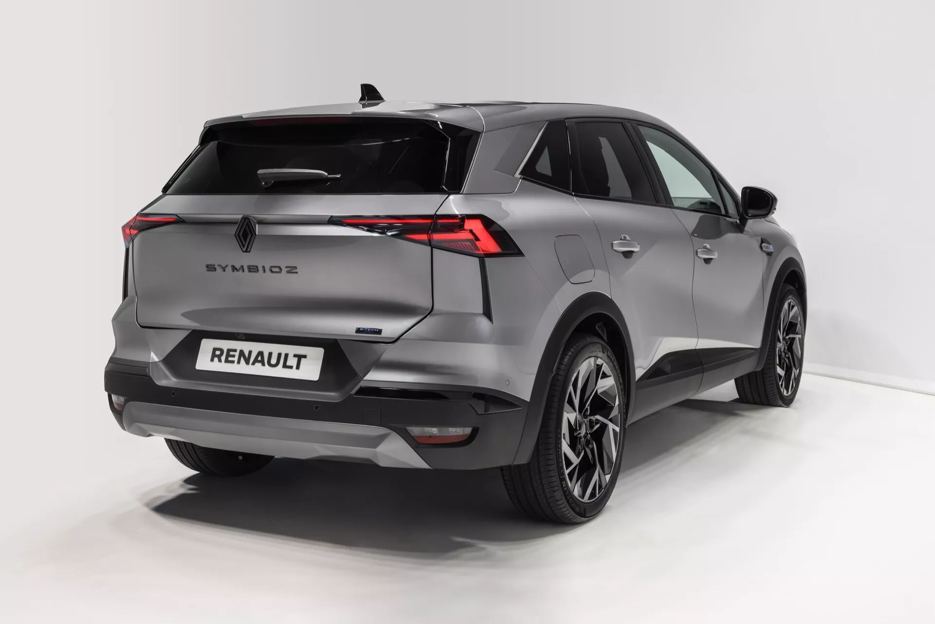 Bilden visar en modern SUV sedd från trekvarts bakperspektiv, som framhäver den skulpterade bakre och sidoprofilen. Distinkta egenskaper inkluderar horisontellt utsträckta LED-bakljus, en lutad bakruta med en integrerad spoiler, sensorer och kamera i bakre stötfångaren för säkerhet samt lättmetallhjul med en flerpelsead design. Fordonet är målat i en metallisk färg som framhäver kurvorna och den vinklade designen. Märkeslogotypen och emblemet är tydligt placerade på bakluckan, vilket indikerar olika moderna bekvämligheter som nyckellöst inträde, bakre parkeringssensorer och avancerade belysningssystem.