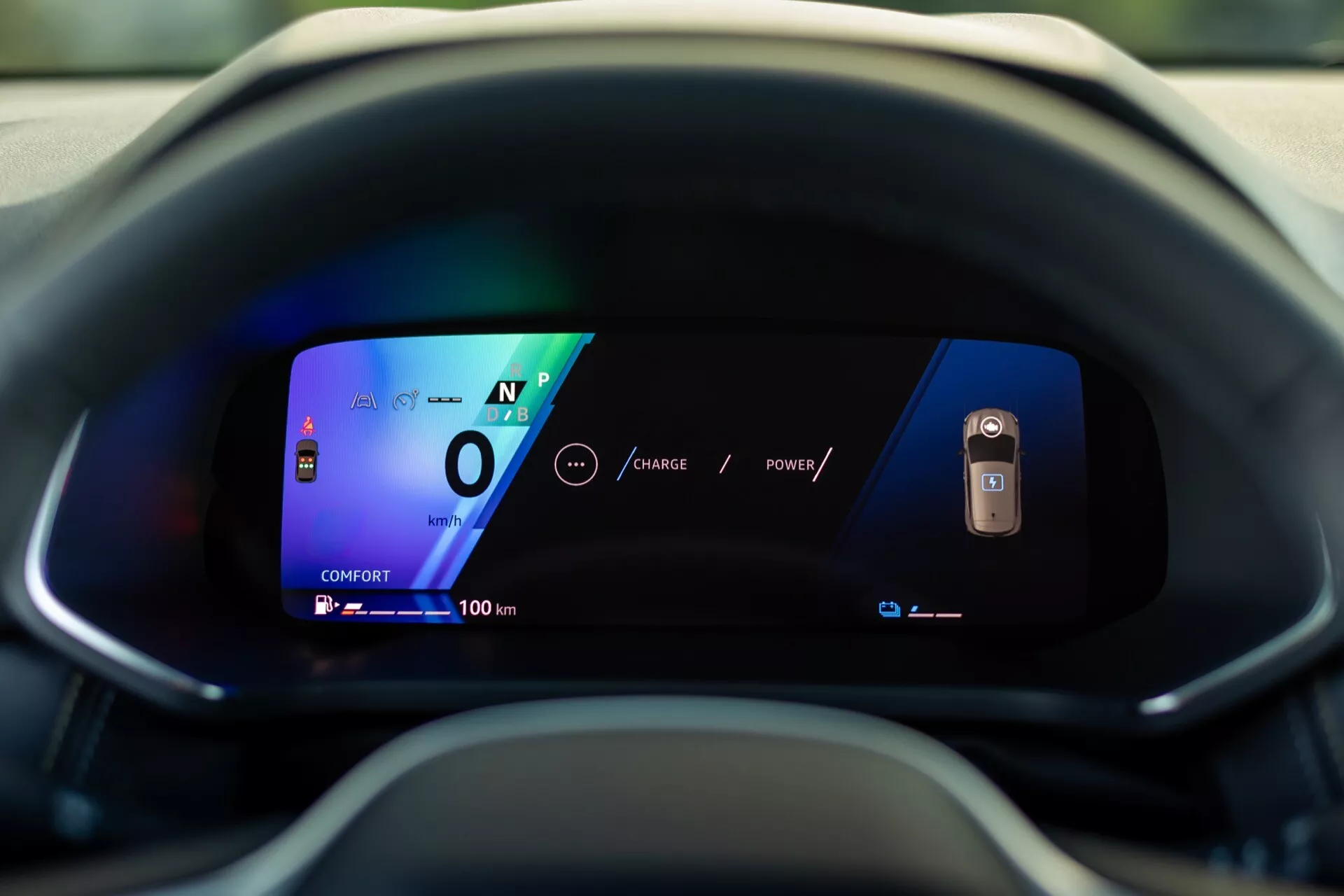 Närbild av den digitala instrumentpanelen i Renault Symbioz 2024, sedd från förarsätet. Skärmen, med livliga färger och tydlig grafik på en böjd skärm, visar bilen i neutralläge med en hastighet på 0 och en räckvidd på 100 km, vilket understryker dess avancerade, sannolikt elektriska teknologi och moderna UI-design.