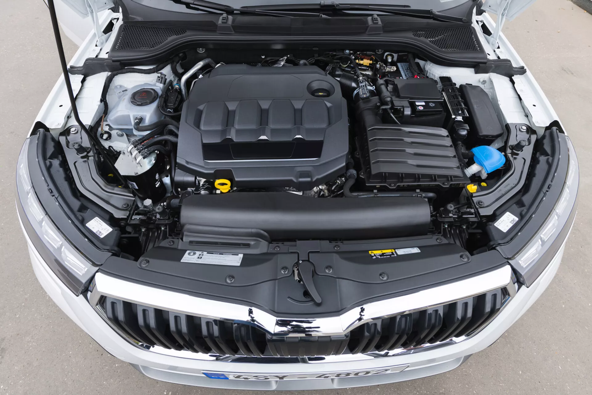 Närbild av 2019 Skoda Kamiqs öppna motorutrymme som visar motorlock, plastsköldar, vätskebehållare och elektriska ledningar utan synliga exteriöra designdelar