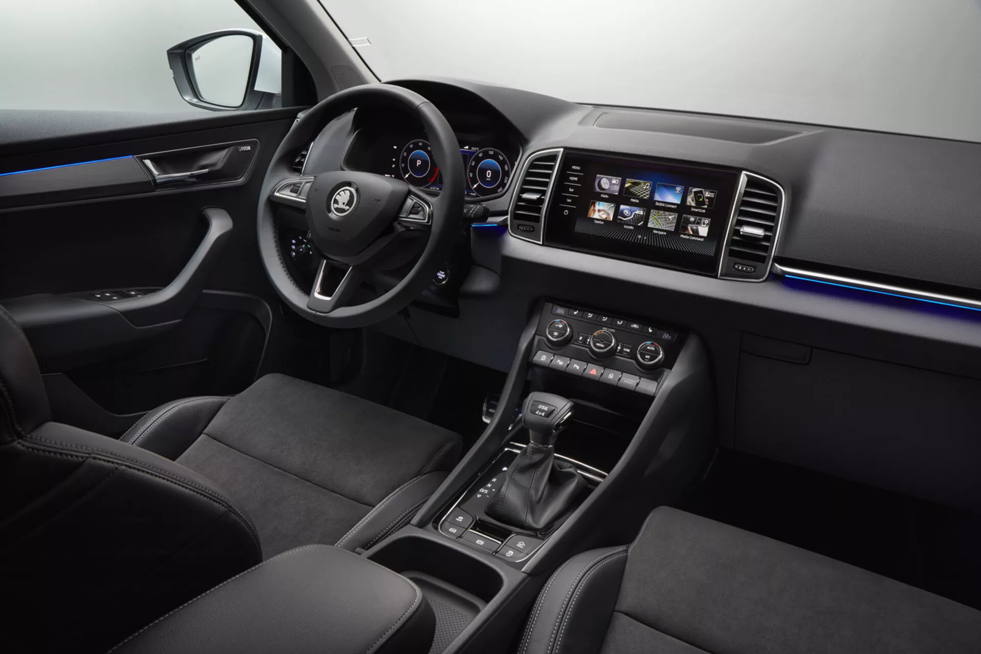 Interiör i Skoda Karoq 2017 med multifunktionsratt i läder med logotyp, digital instrumentbräda, pekskärmsbaserat infotainmentsystem, dubbelzons klimatkontroll, automatisk växelspak, omgivningsbelysning, ergonomiska lädersäten och kontroller för eldrivna fönster.