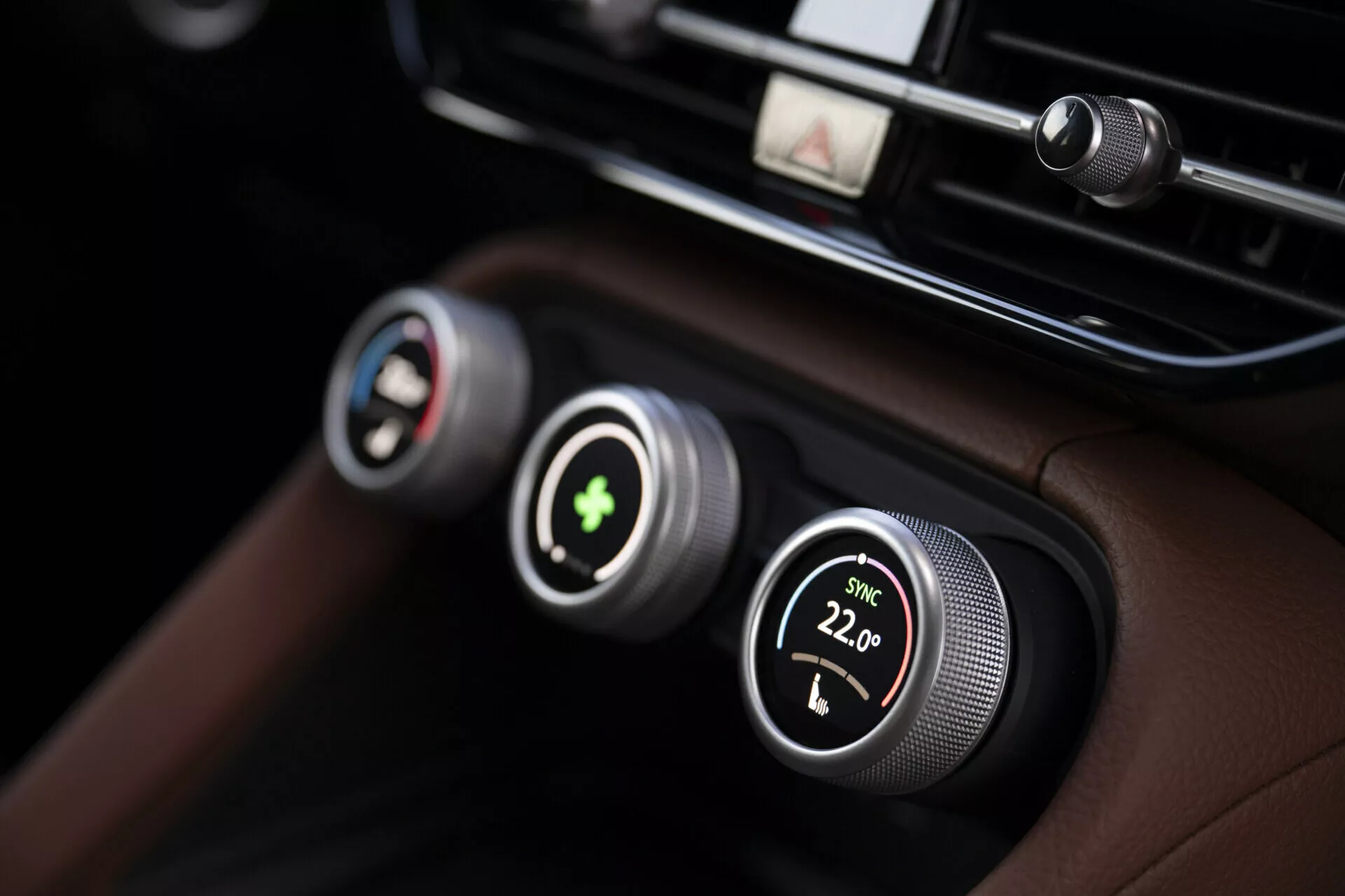 Närbild av Skoda Kodiaq 2024s klimatkontrollsystem med dubbla zoners temperaturkontroller med metallknappar och digitala visningar, mot en premium svart läderinstrumentbräda