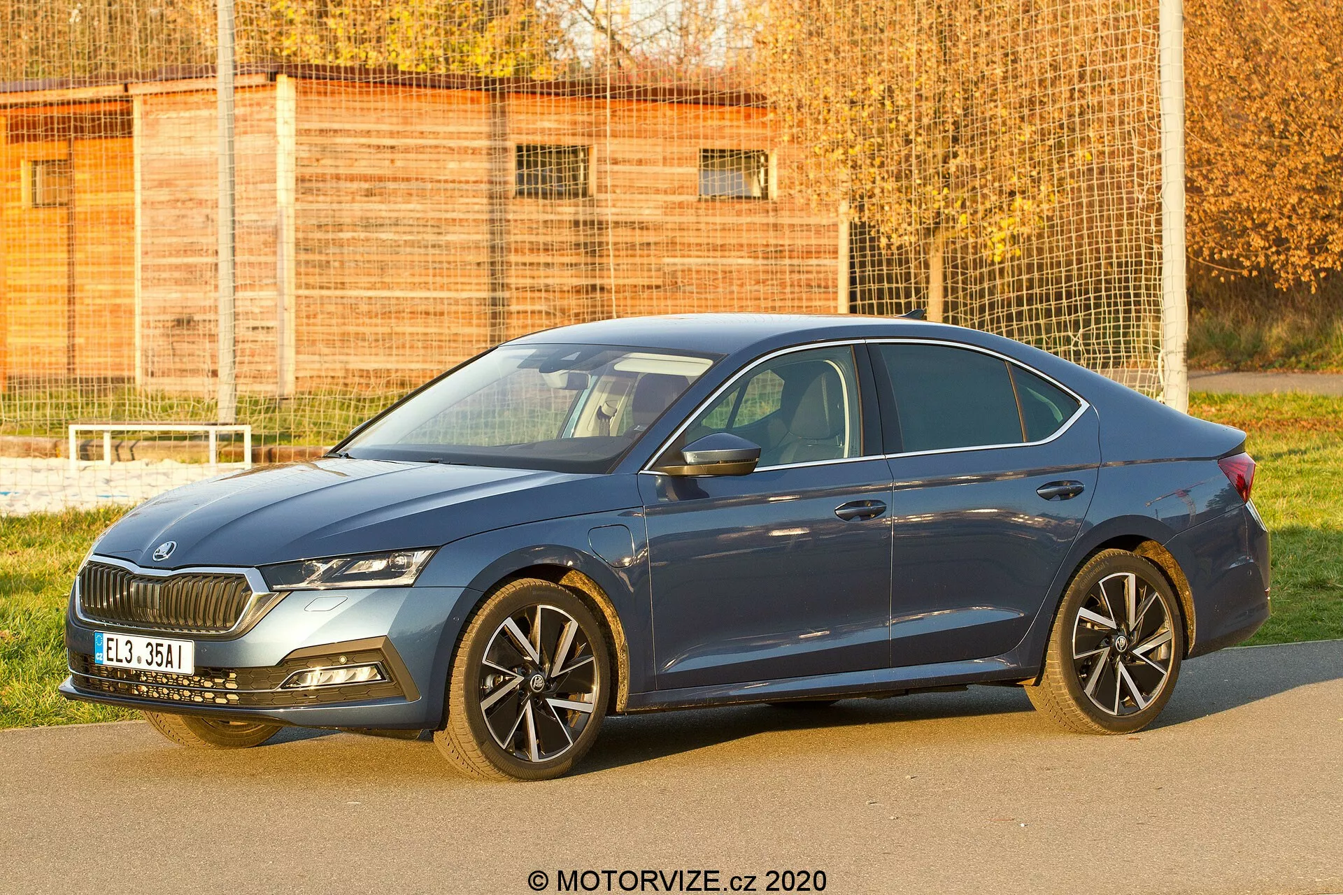 Bild av en fyrdörrars sedan Skoda Octavia 2020 från en trekvarts frontvinkel som visar dess främre grill, strålkastare, motorhuv, hjul, förardörr och en del av bakdelen. Bilden fångar det distinkta grilldesignen, de eleganta strålkastarna som troligen har LED- eller adaptiva belysningssystem, flerspokslegeringshjul som antyder sportighet eller lyx, lågprofilade däck och sidobackspeglar med integrerade blinkers. Bilens aerodynamiska linjer och blå färg är tydligt synliga och framhäver design- och teknologifunktioner som är lämpliga för bilsammanhang och moderna fordon.