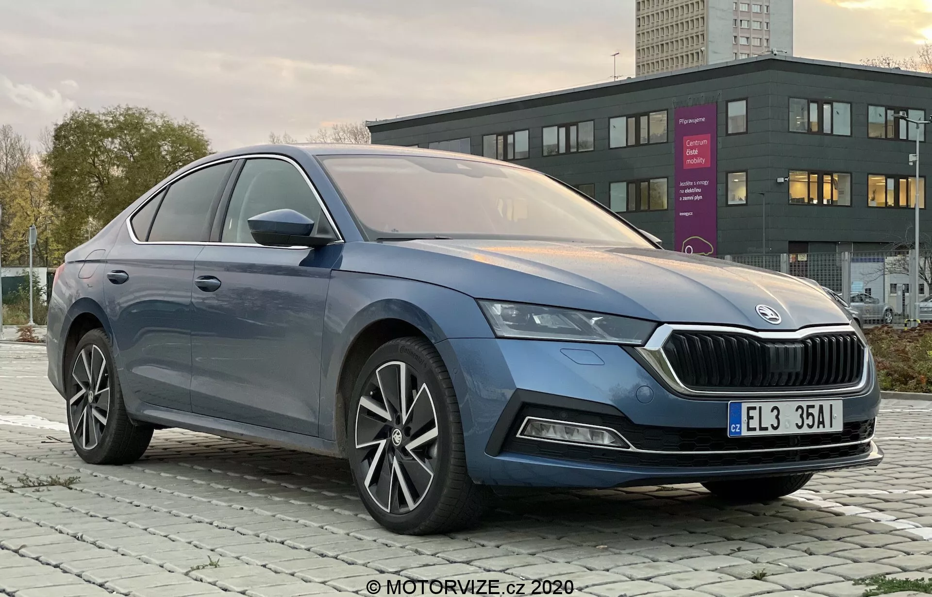Professionell bild av fyrdörrarsmodellen Skoda Octavia Limousine 2020 tagen från en trekvarts vinkel från vänster fram, som tydligt visar den distinkta grillen, eleganta LED-strålkastare, främre stötfångare med eventuella dimljus, släta karosslinjer, fler-ekrade aluminiumsfälgar, sidobackspeglar med integrerade blinkers samt premium fönsterlister i krom i en stads- eller förortsmiljö vid gryning eller skymning.