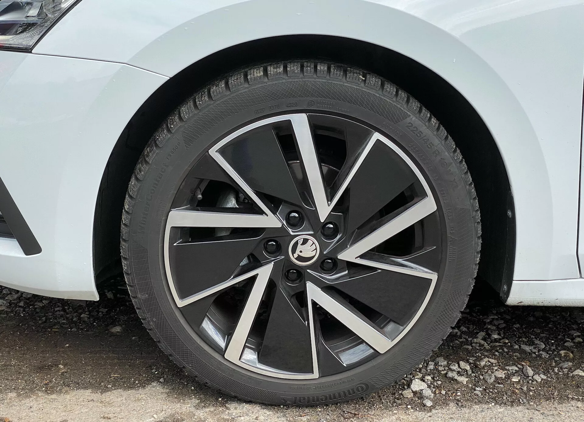 Närbild av framhjulet på en 2020 Skoda Octavia limousine, som visar en modern fem-ekrad lättmetallfälg med tvåfärgad finish och bearbetade ytor på ekrarna, fångad från en 45-graders vinkel som framhäver dess dynamiska, turbinliknande design och det synliga slitbanemönstret på ett året runt-däck.
