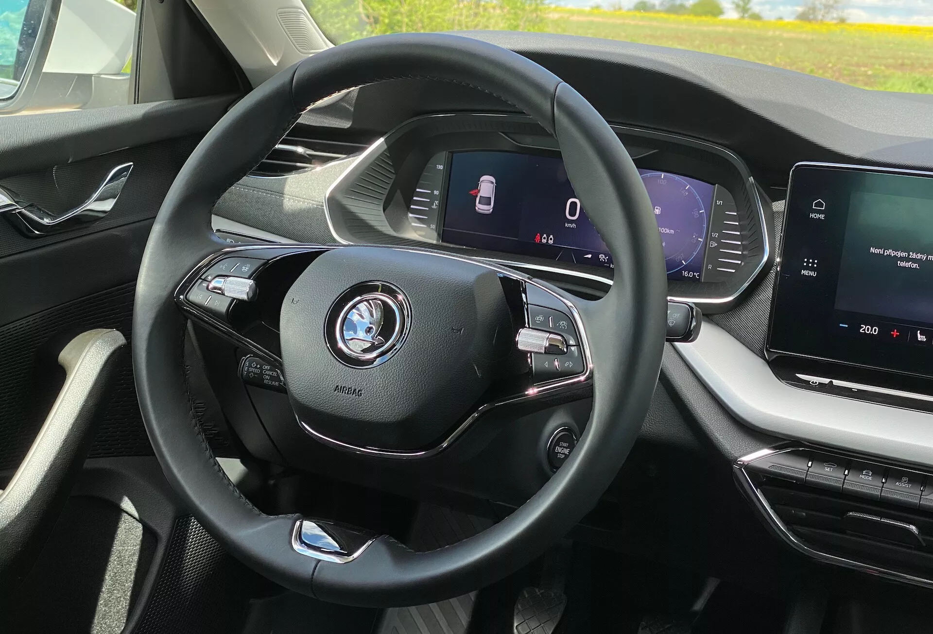 Interiörvy av Skoda Octavia 2020 från förarens perspektiv; centrerad modern treekrad ratt med multifunktionella kontroller för media och telefon, synligt bilmärke; helt digital instrumentpanel som visar hastighet och säkerhetsfunktioner som filhållningsassistans; mittkonsol med infotainment pekskärm, visar mediasystem och möjlig navigering; modern, exklusiv interiör med rena linjer och väl designade ventilationsöppningar; ingen utsikt över exteriören, bara förarens omedelbara miljö i hytten; indikationer på avancerad billteknologi som adaptiv farthållare och anslutningsfunktioner.