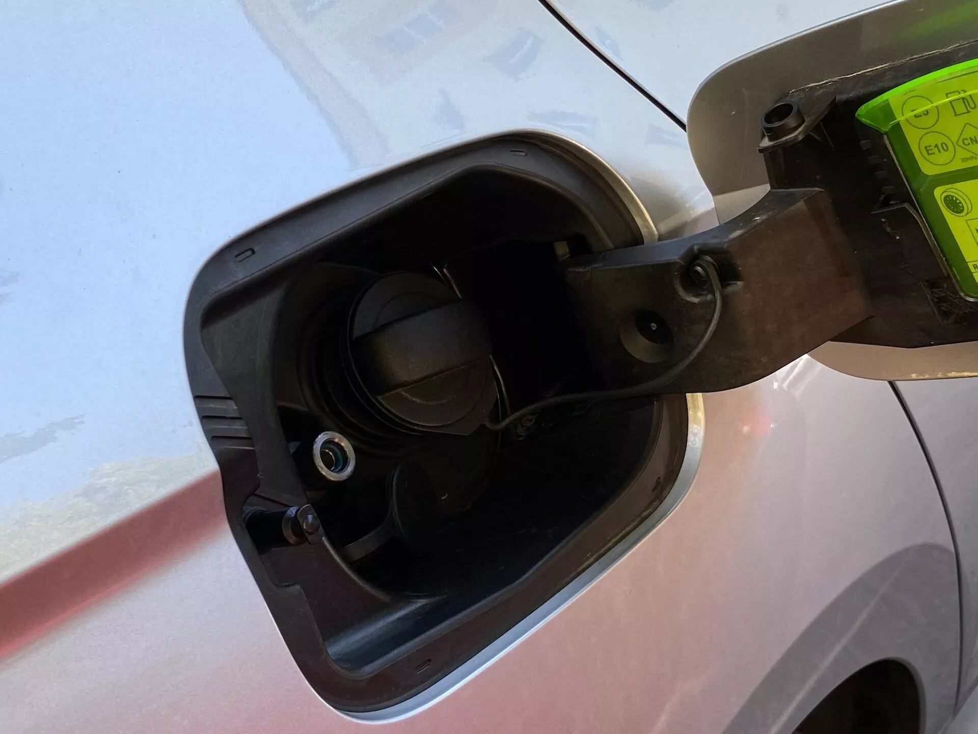 Närbild på bränslepåfyllningsområdet på en Skoda Octavia Limousine 2020, som visar det öppna bränslelocket fäst med ett flexibelt band, de omgivande fordonsdetaljerna och den nedsänkta bränslepåfyllningshalsen med en synlig ventil, allt sett från en lätt nedåtvinkel.