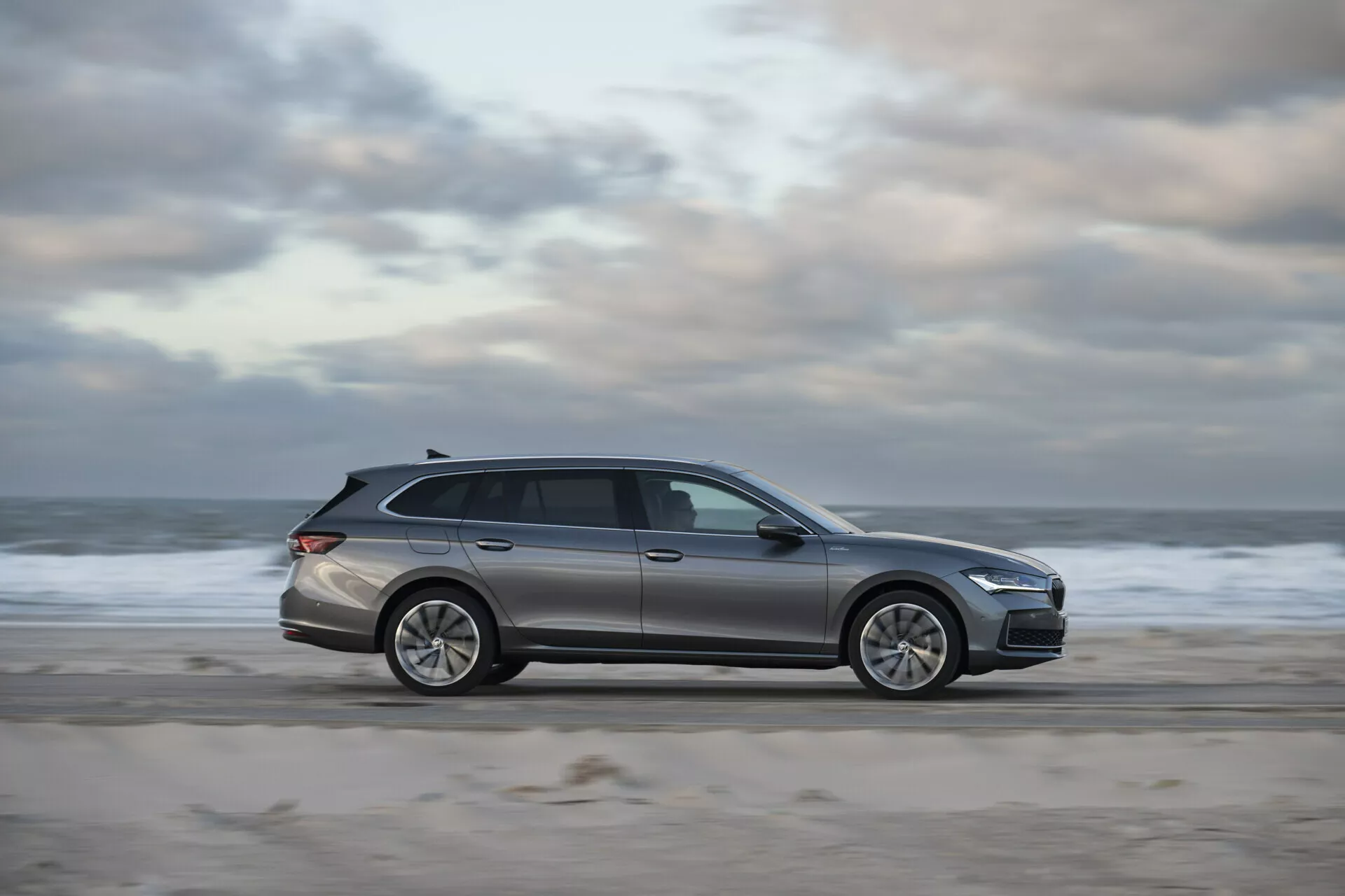Skoda Superb Combi 2024 parkerad på en strand med sandig och vattnig bakgrund, framhäver dess eleganta design, modern LED-belysning och avancerade tekniska funktioner i en fridfull utomhusmiljö