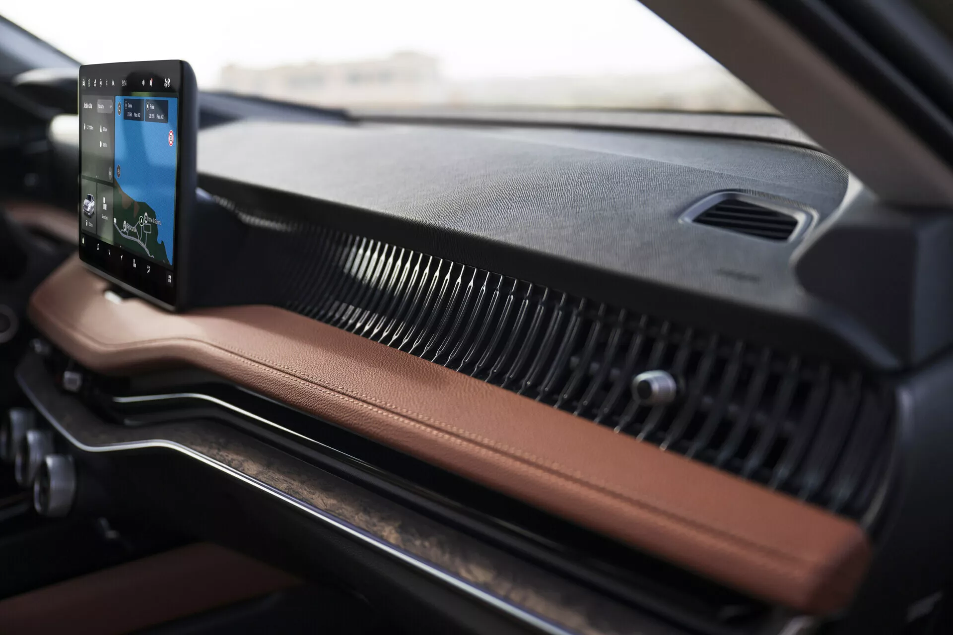 Närbild av interiören på instrumentbrädan i Skoda Superb 2024 som lyfter fram ett vertikalt orienterat pekskärmsinformationssystem med integrerad navigation, läder- och texturerade plastmaterial, samt moderna horisontella ventilationsgaller.