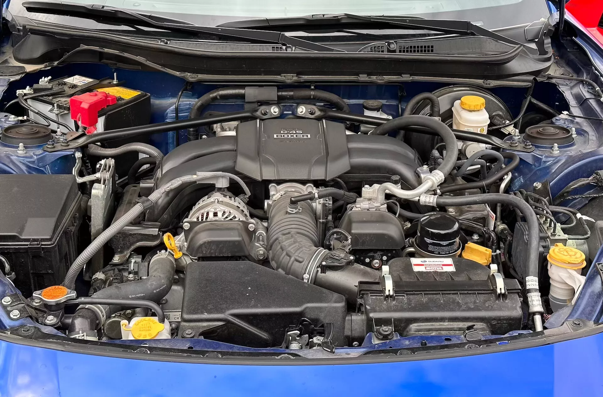 Detaljerad vy över motorutrymmet i Subaru BRZ 2023 med BOXER-motor, batteri, vätskereservoarer och luftintagssystem synliga